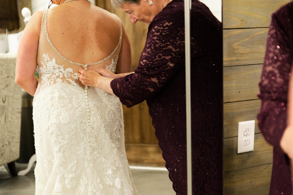 Mom buttoning up the bride's dress at The Parker Mill Wedding Venue
