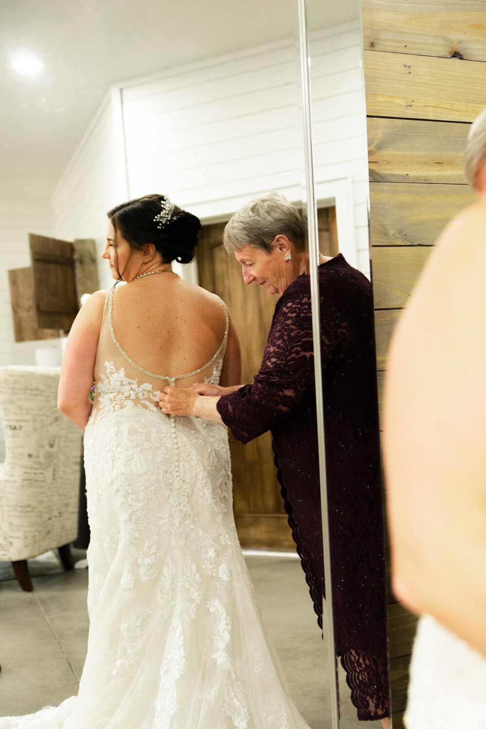Bride having her dress buttoned up by her mom at The Parker Mill Elopement