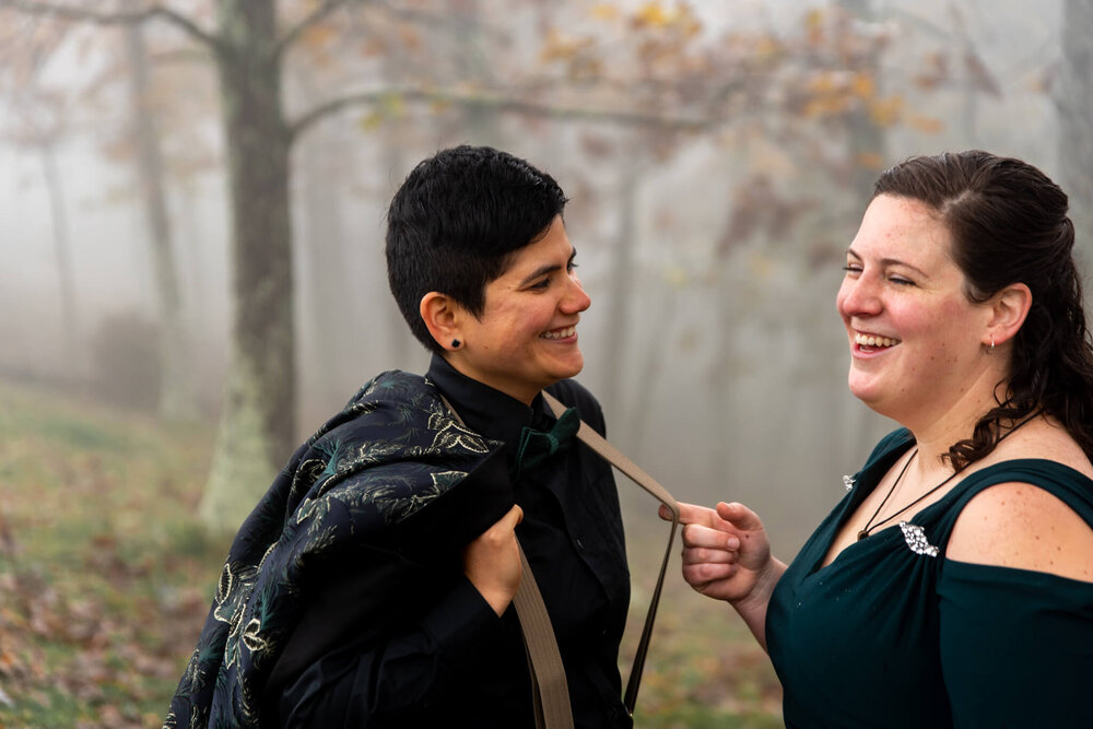 bride playing with her partner's suspender straps before their elopement ceremony