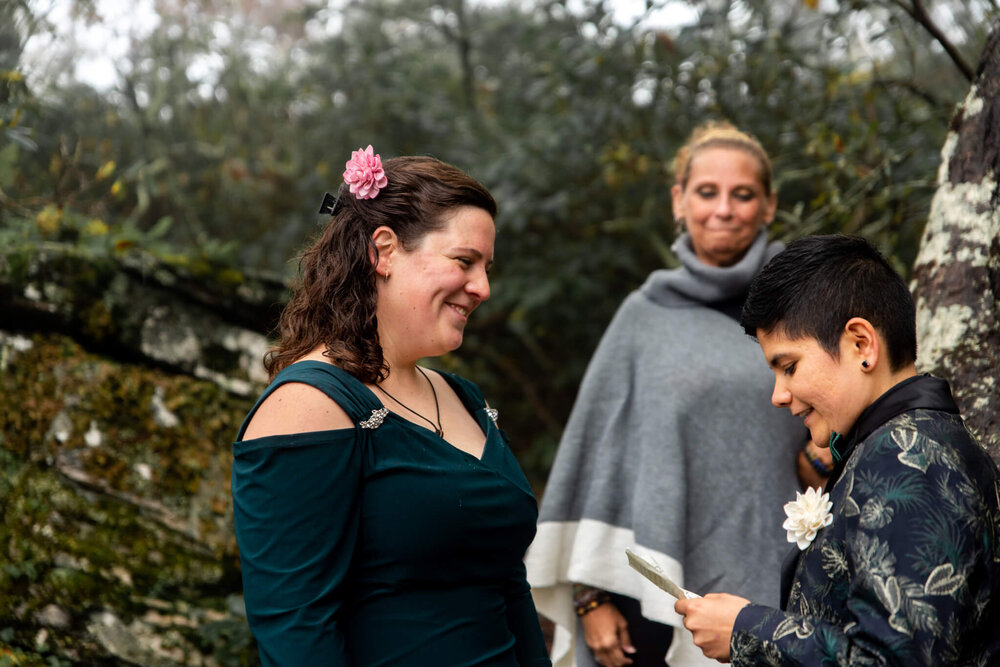 bride smiling as she listens to her partner read her vows during their elopement