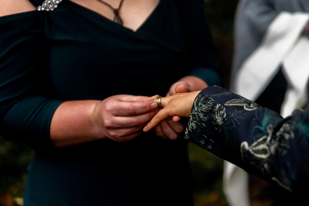Bride placing wedding ring on her bride's finger during their wedding elopement ceremony