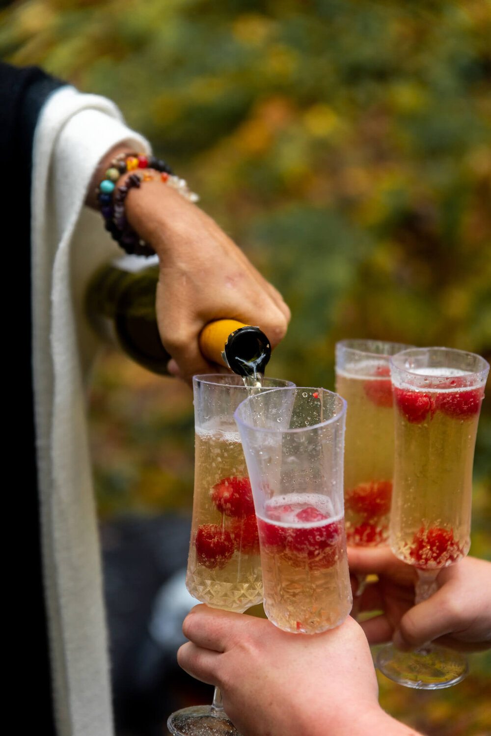 Champage being poured into champagne flutes filled with raspberries during elopement reception