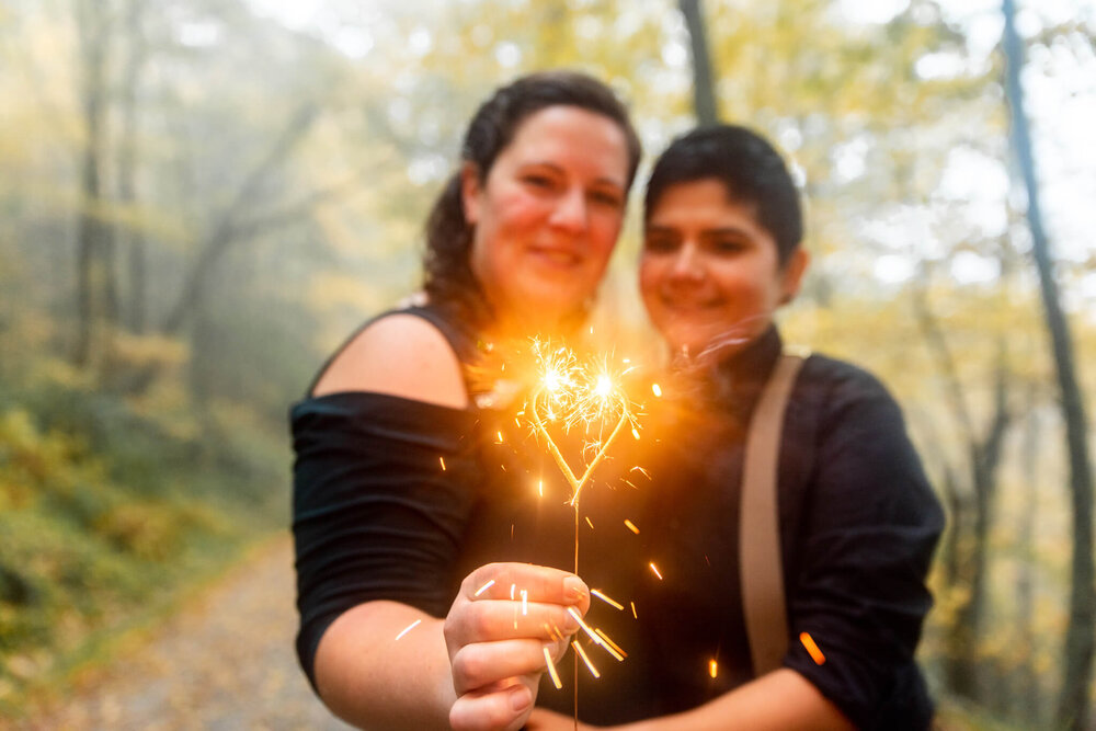 gay elopement couple holding heart shaped sparkler