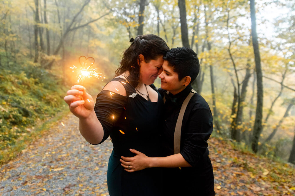 wedding couple sharing an intimate moment of love while holding a heart shaped sparkler 