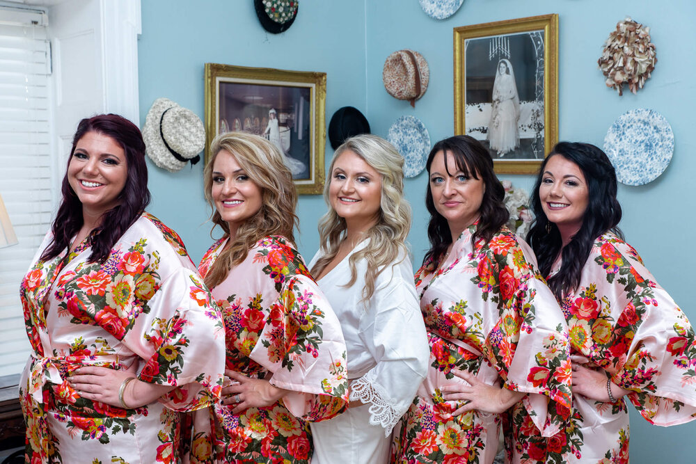 bridal party posing with bride in robes in the gassaway mansion bridal suite
