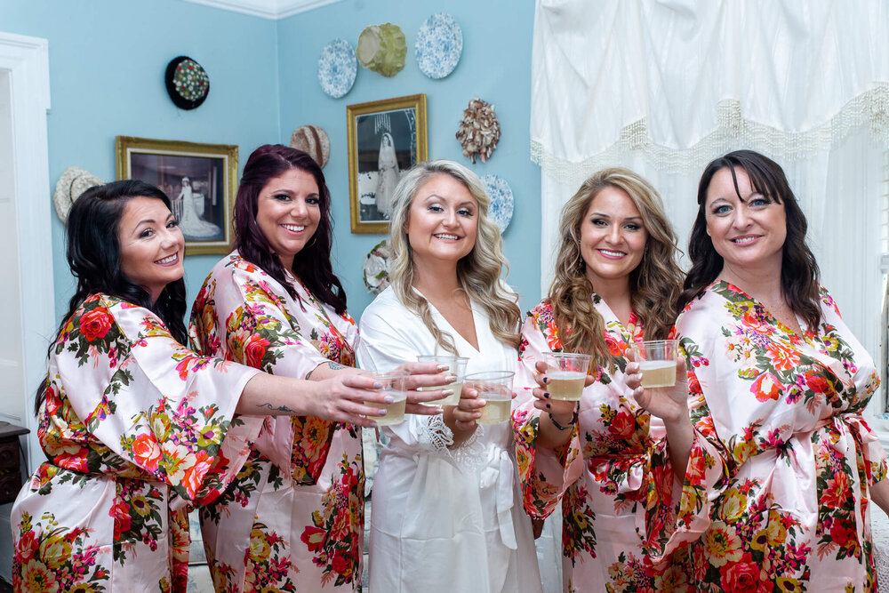 bridal party posing with bride in robes in the gassaway mansion bridal suite