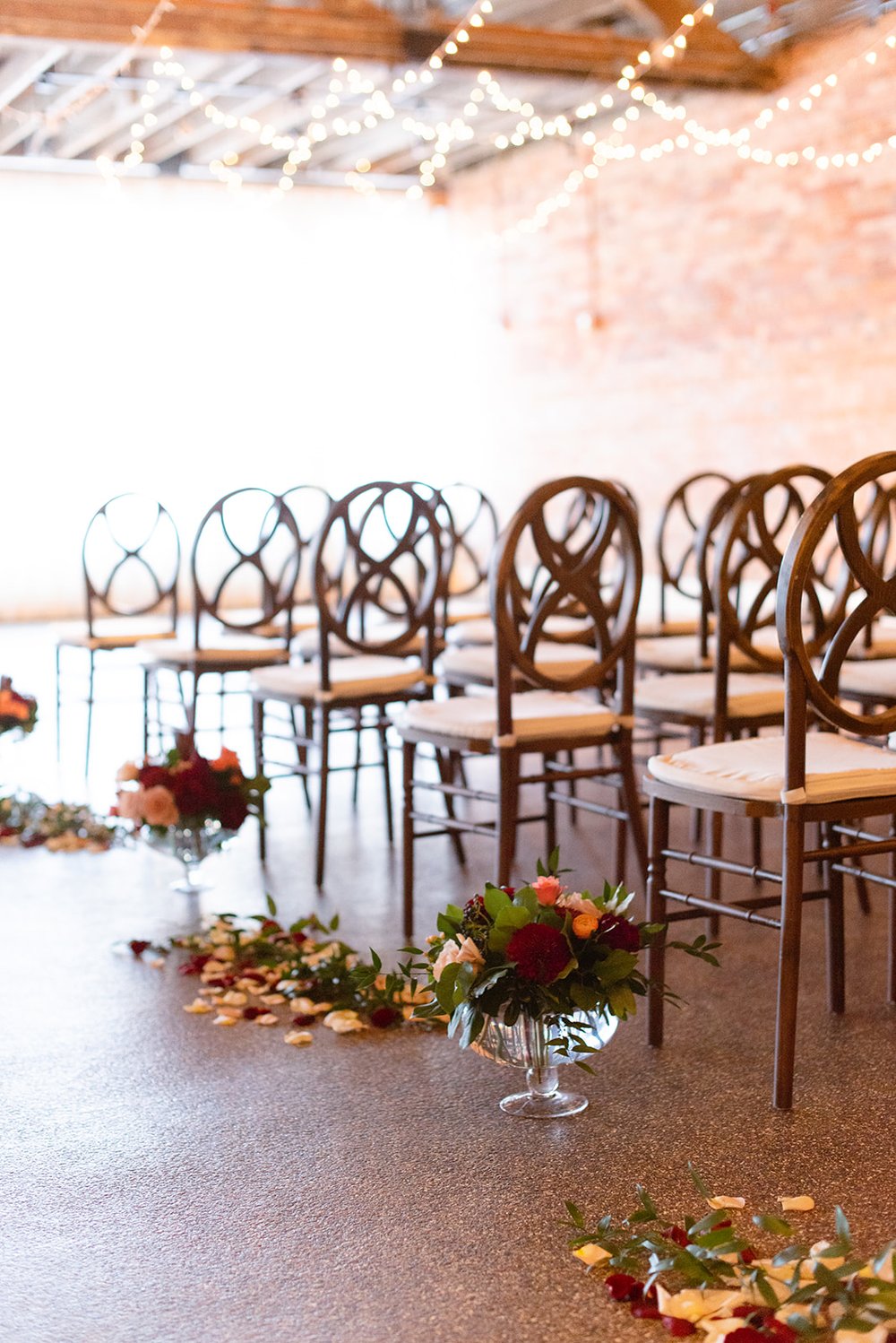 aisle of the venue for a fall wedding with flowers and chairs