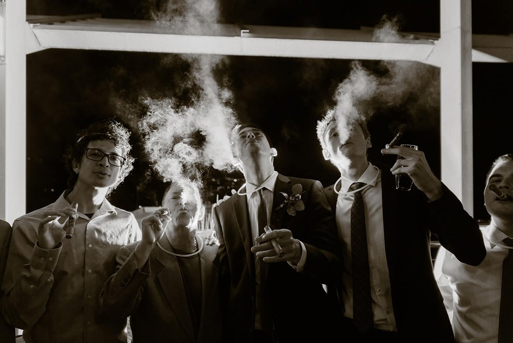 groom and groomsmen smoking cigars at asheville wedding venue the capital club