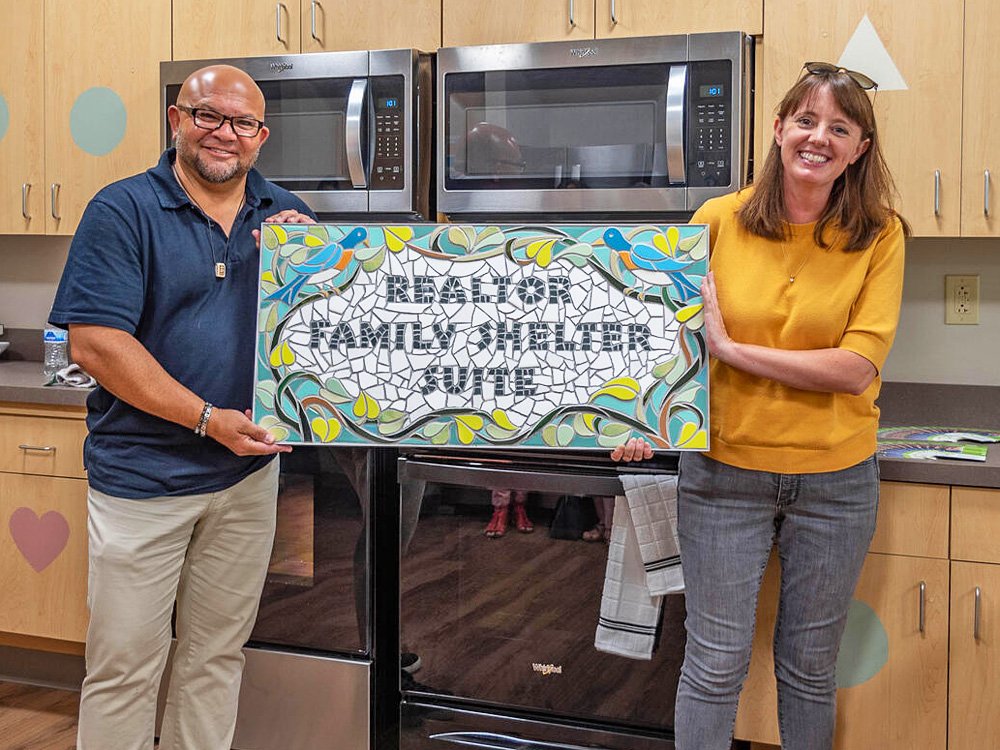  Bloomington Realtor Chris Cockerham (left) and New Hope for Families Executive Director Emily Pike (right) hold the plaque to be installed at the Bloomington Realtor family shelter suite. Photo by Jane Daniels. 