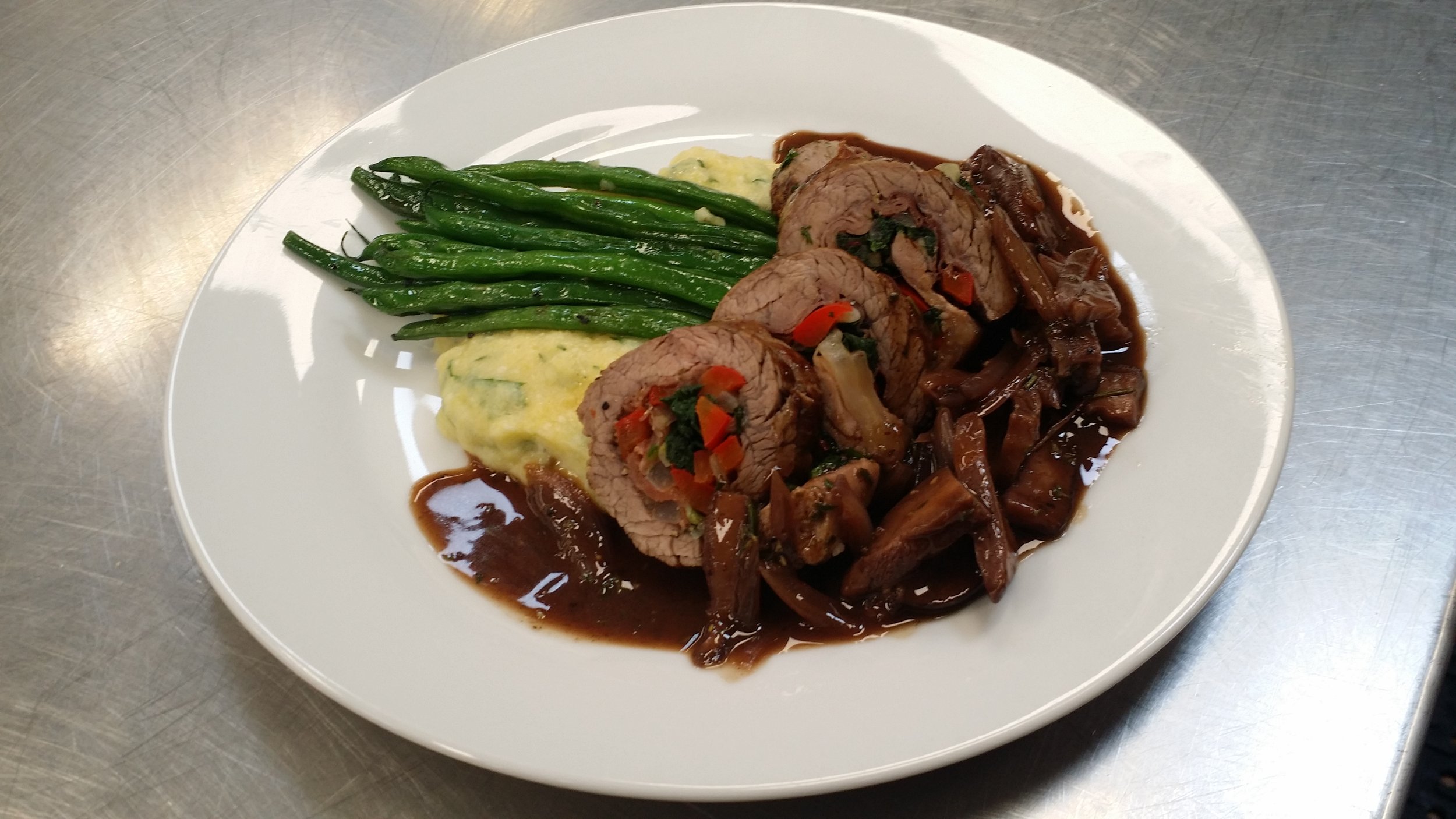Beef Roulade Stuffed with Roasted Red Peppers and Sautéed Spinach served with a Mushroom Demi Glace, Roasted Garlic Mashed Potatoes and Sautéed Green Beans
