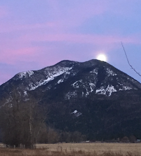 Mountain landscape at dusk with snow patches and visible moon