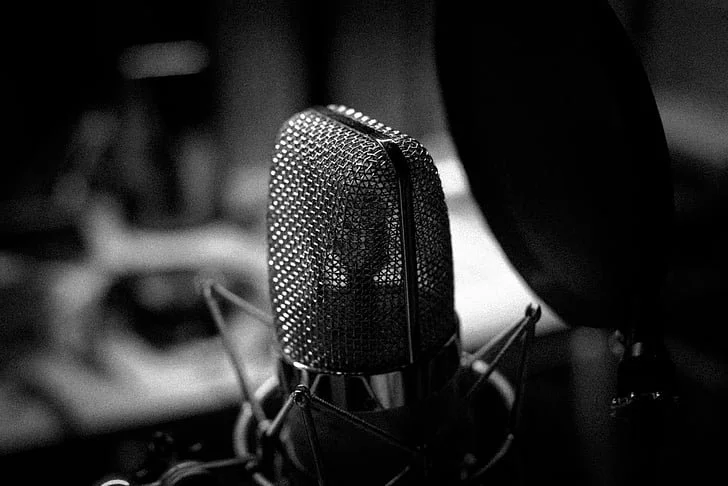 Close-up of a vintage microphone in a recording studio with a pop filter nearby