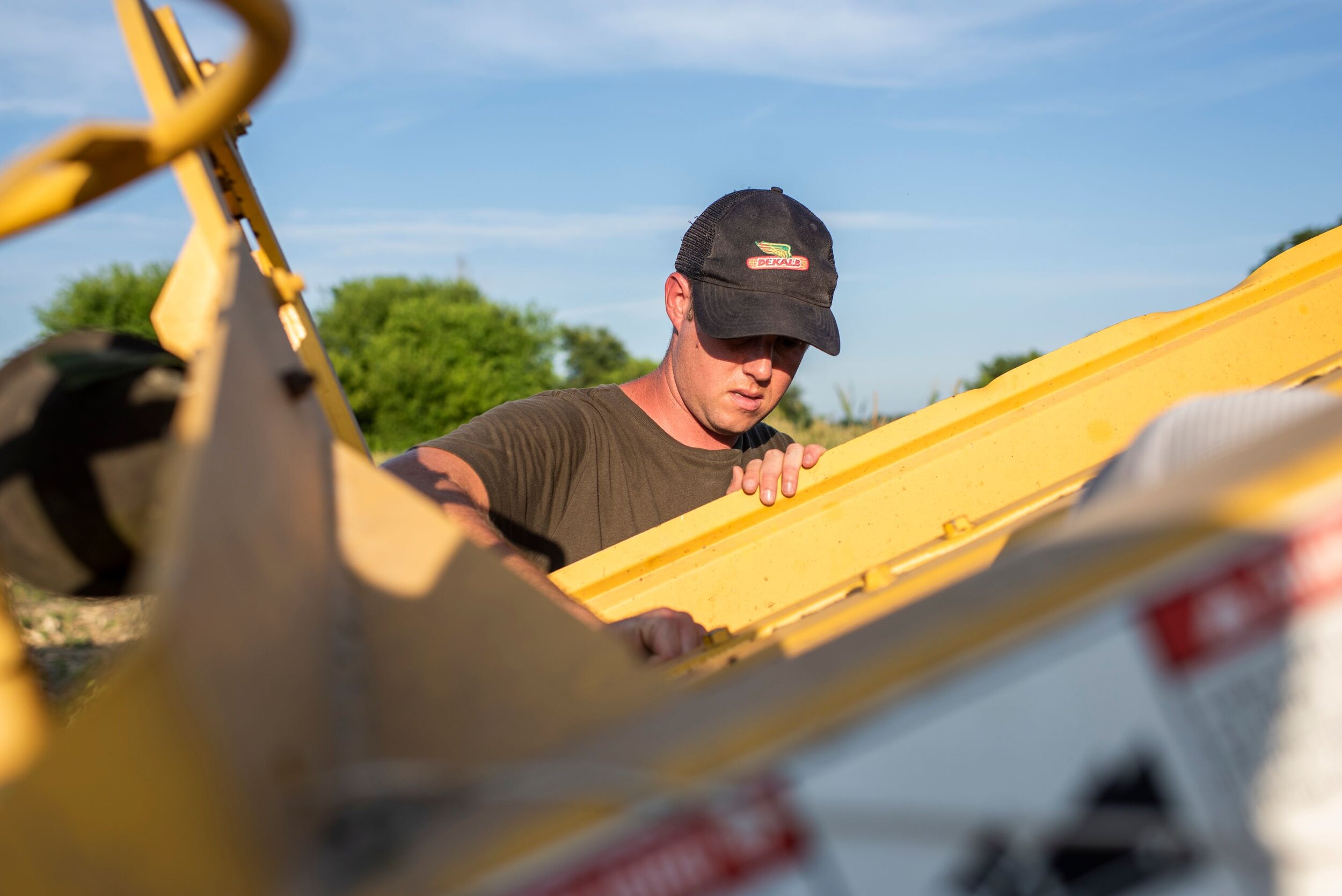 A young male farmer works with equipment to harvest crops