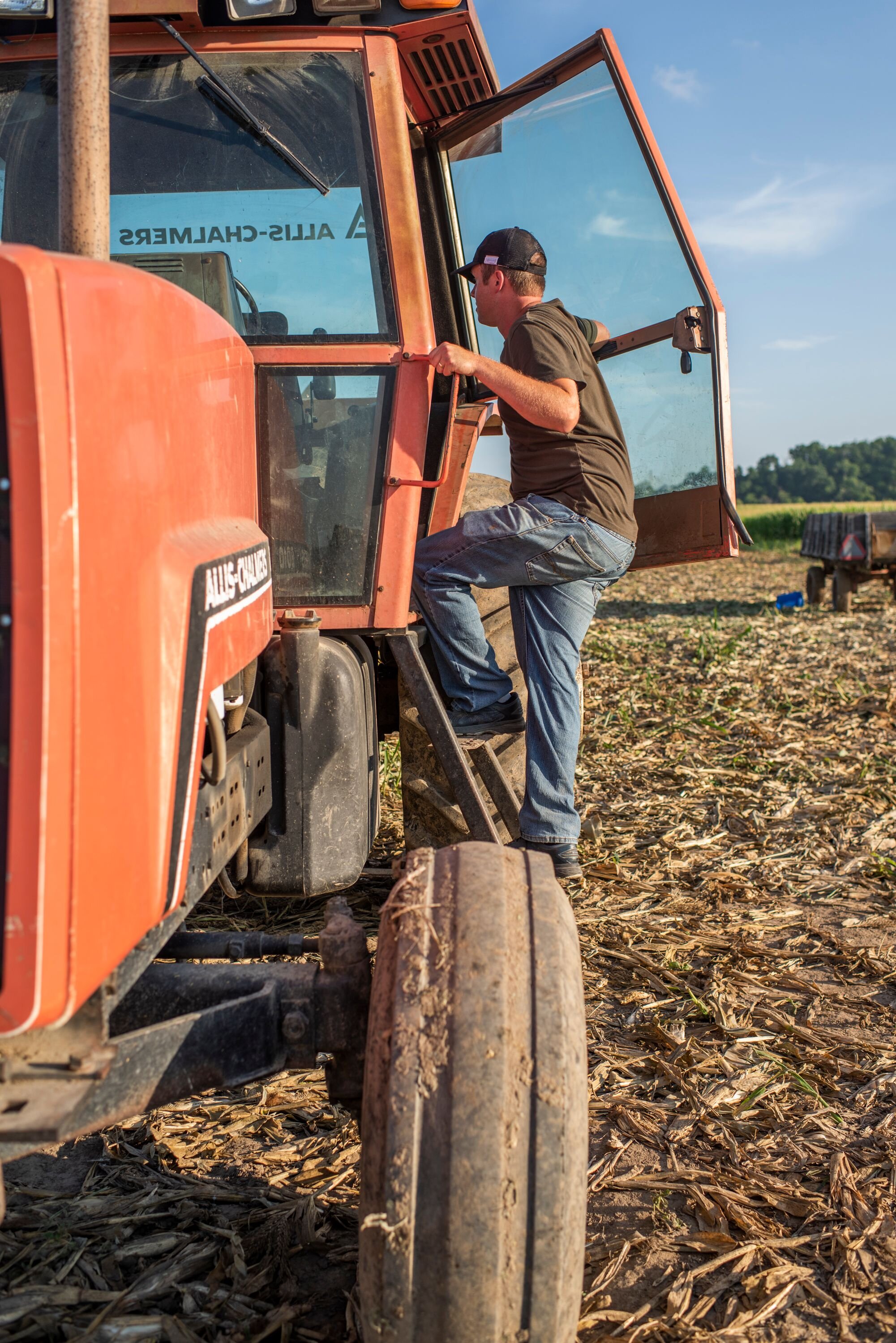 A farmer getting into his orange truck