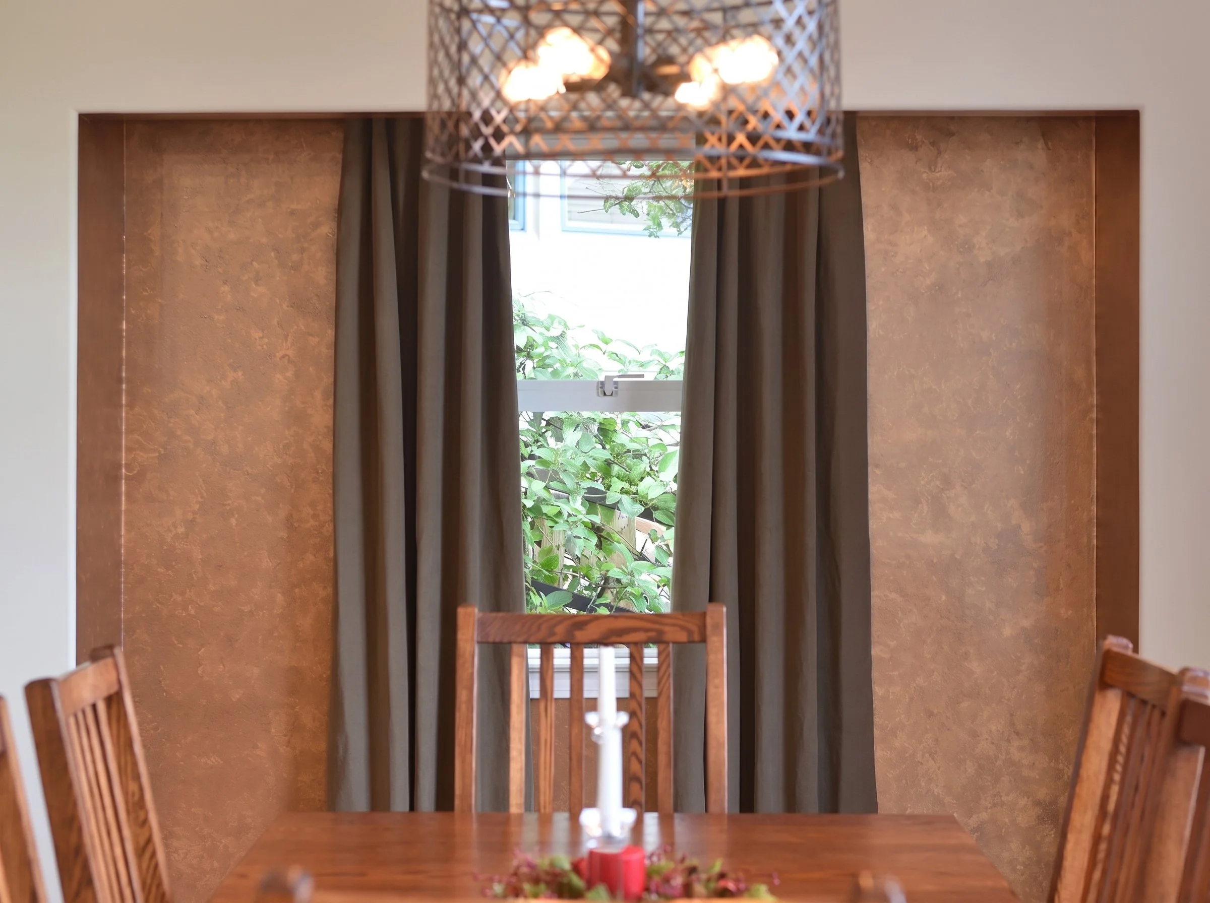 Dining room window with drapes and a chandelier.