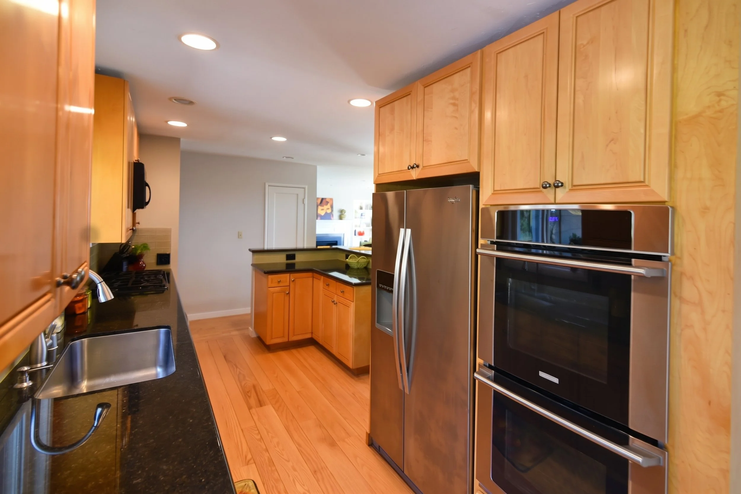 Refrigerator and wall ovens set in maple cabinets.
