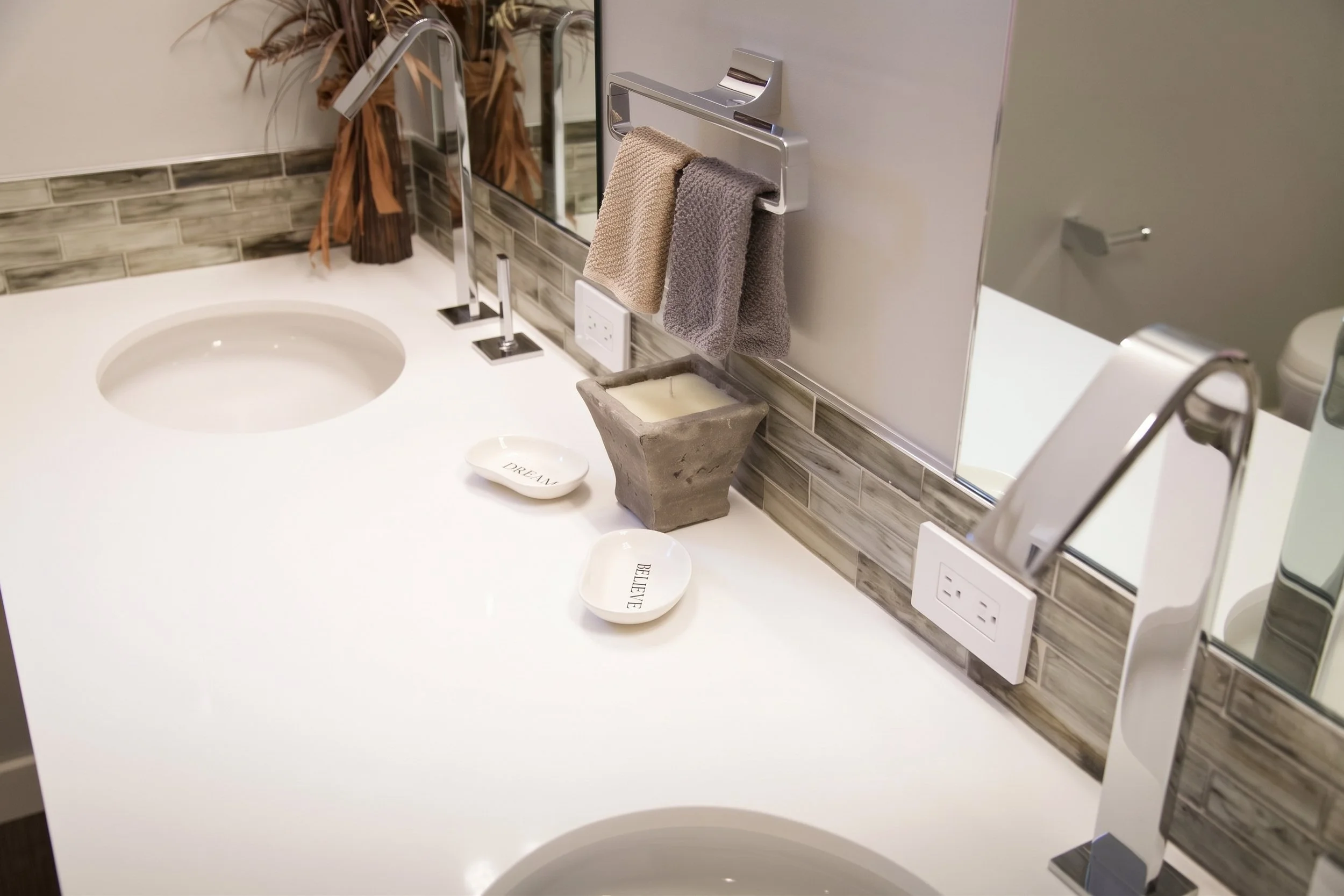 Double vanity with a white counter and a glass tile backsplash.
