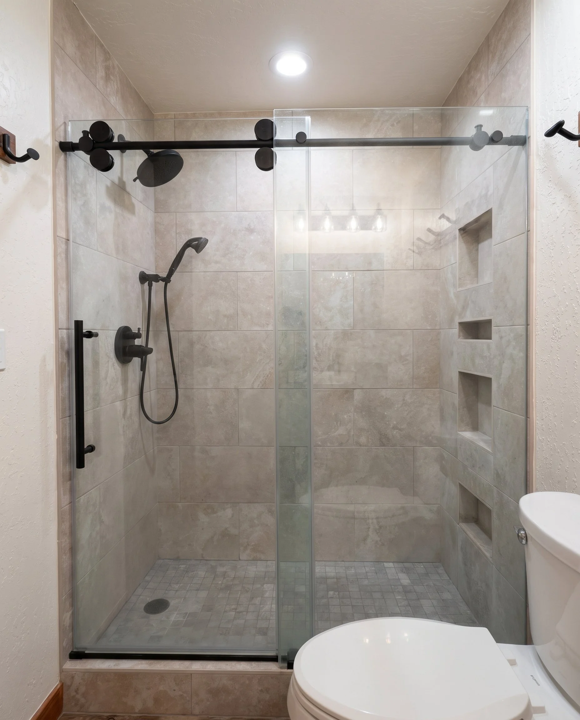 Tiled walk-in shower with a sliding glass door on black barn-door hardware.