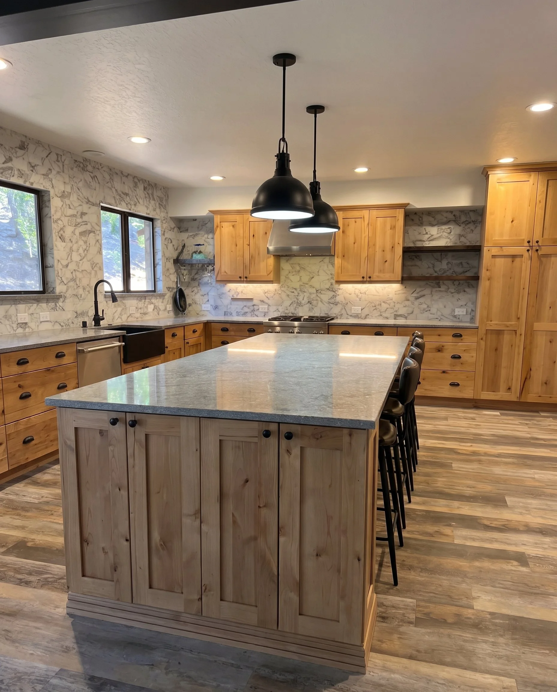 Kitchen island with seating and black pendant lights, seen from the end.
