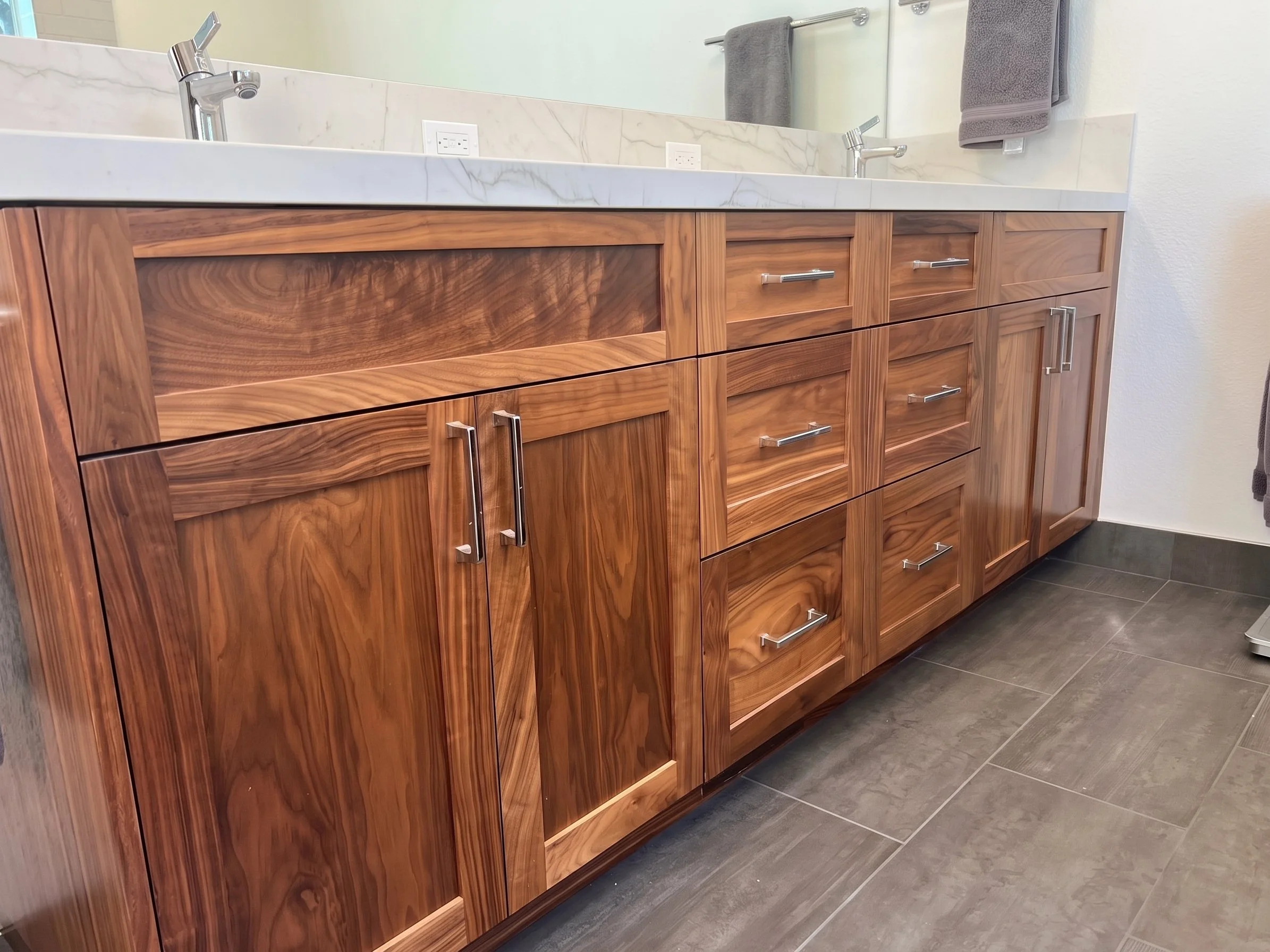 Detail of the dark wood vanity doors and drawers with brushed pulls.