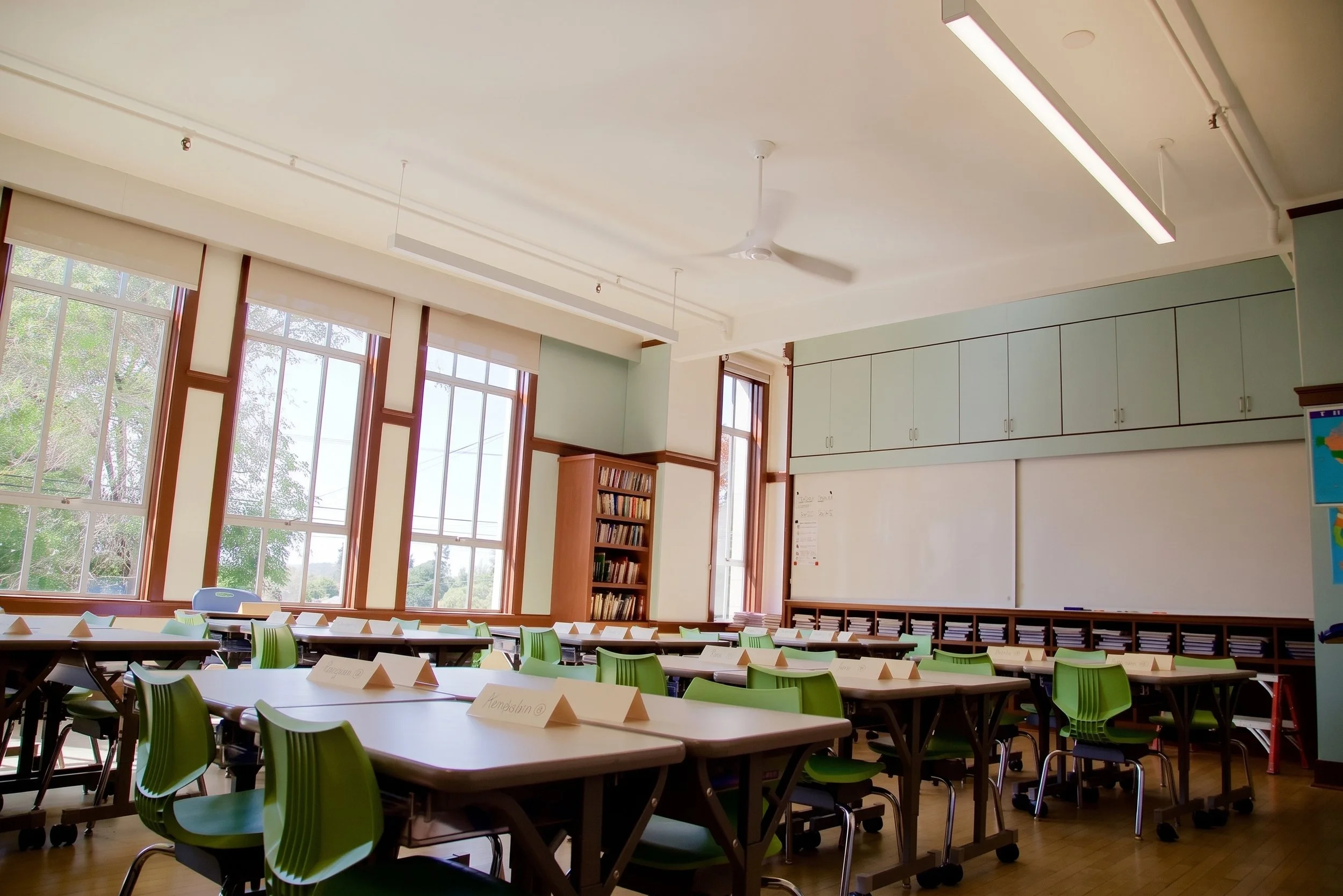 Classroom with full-wall storage cabinets above sliding whiteboard panels.