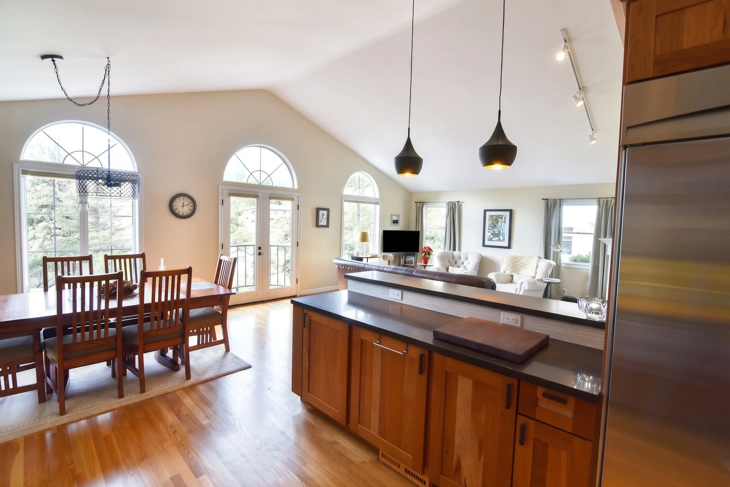 View across the breakfast bar to the dining table and arched windows.