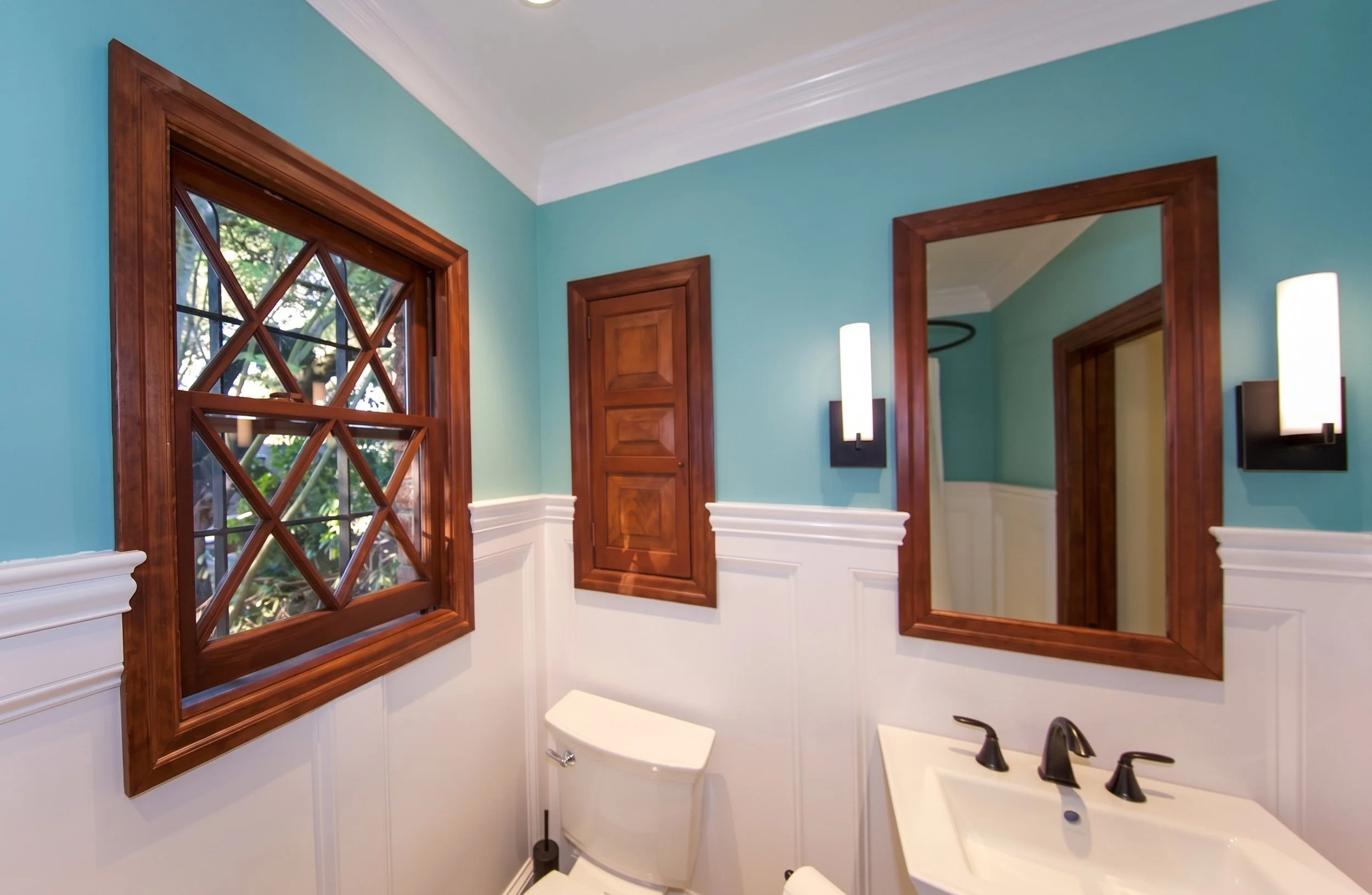 Original wood window with diamond panes beside the pedestal sink.