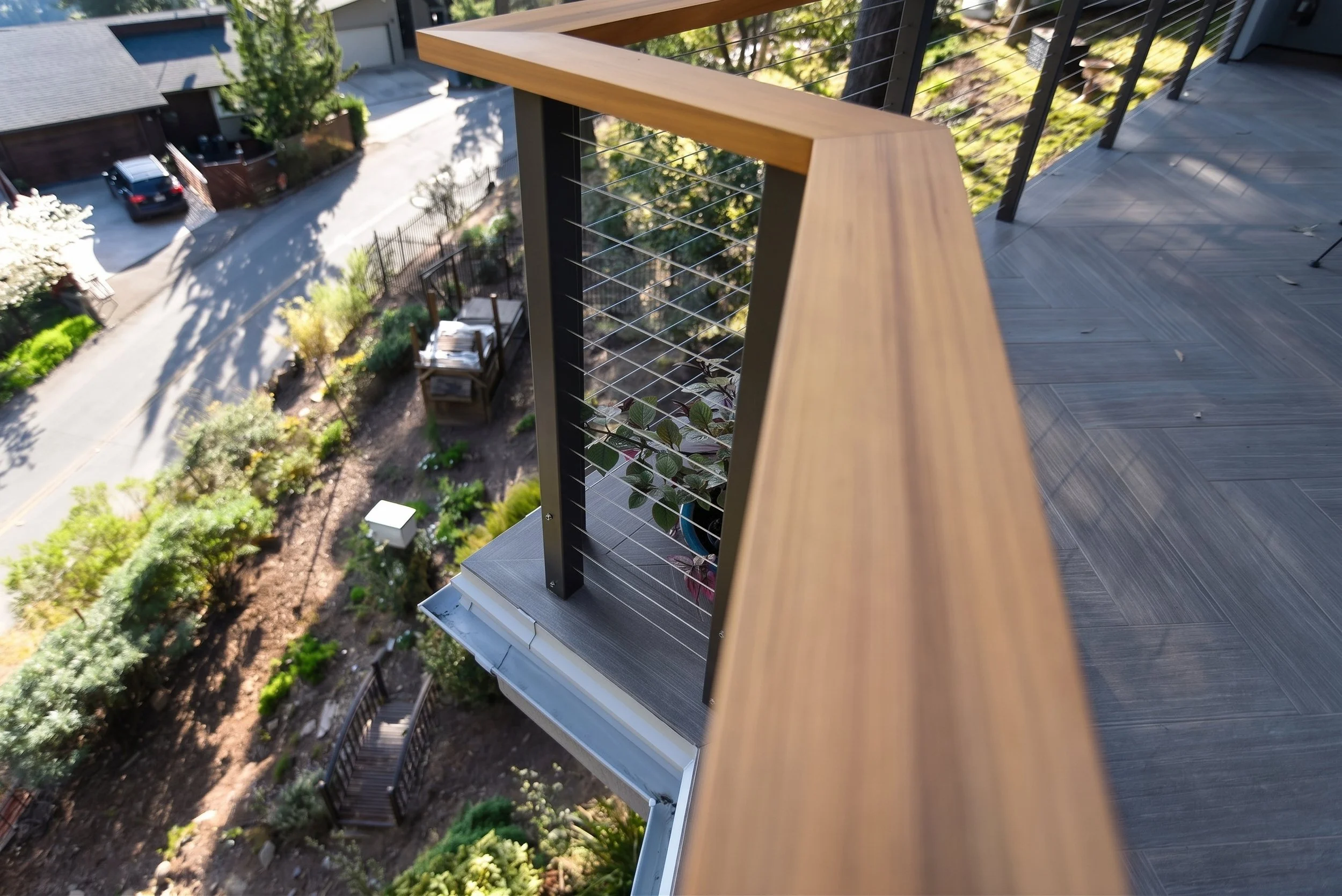 Wood cap rail on the deck railing, looking down the hillside.