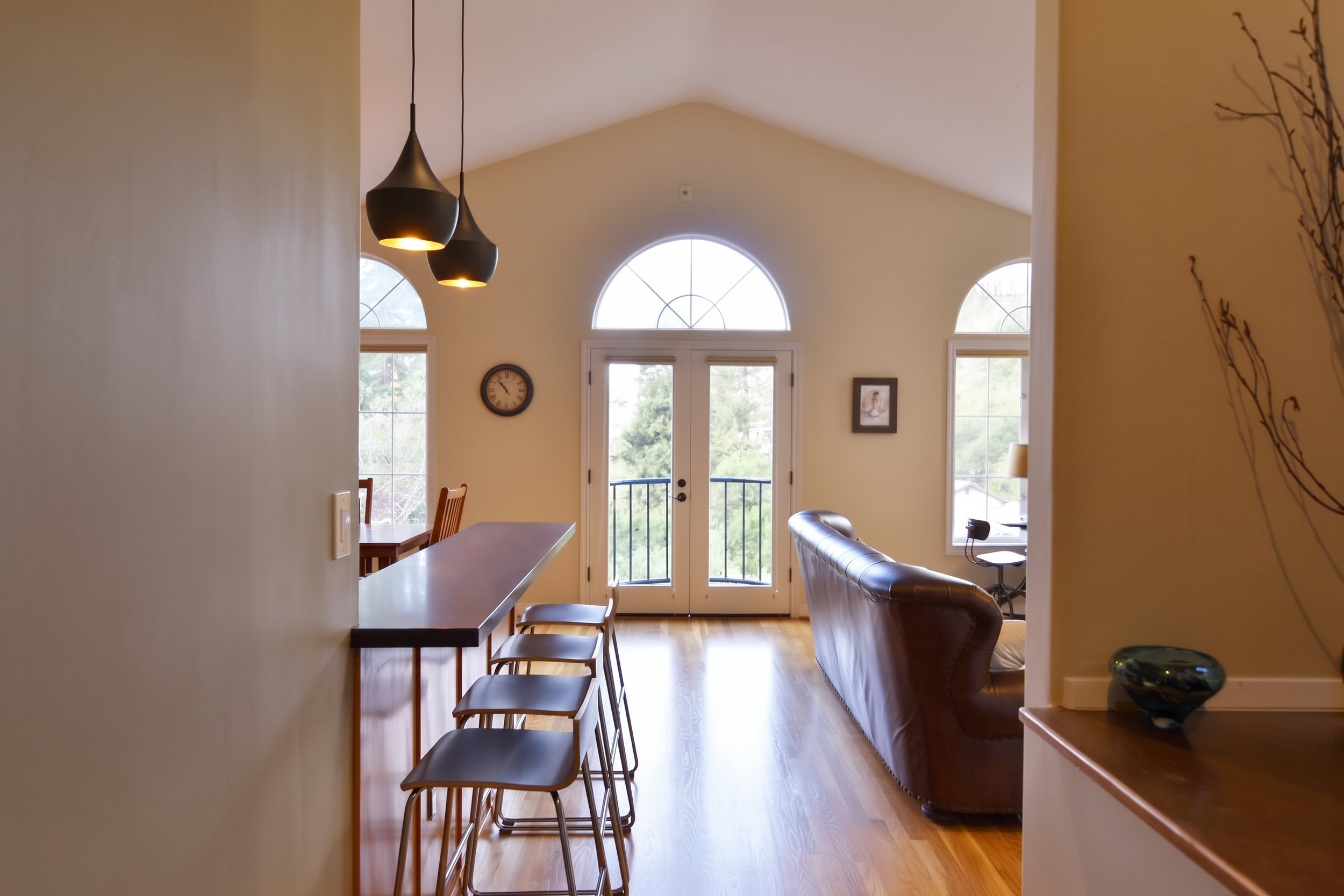 Raised breakfast bar with stools, facing arched windows and doors.