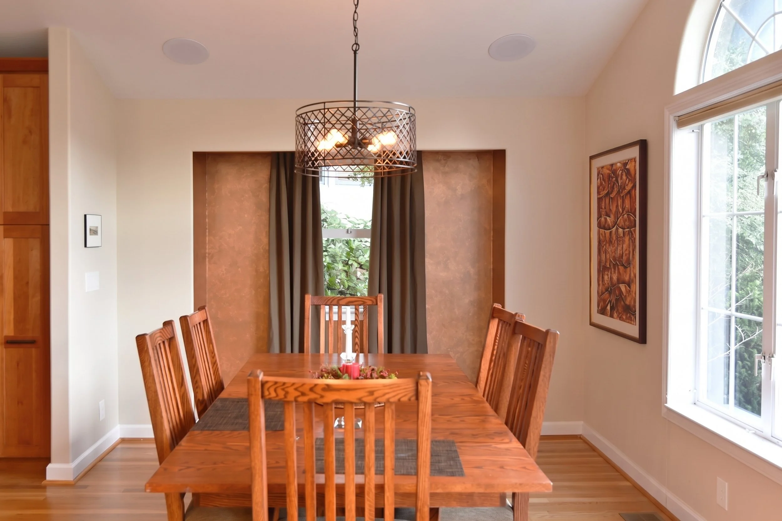 Dining room with a wood table and an arched window.