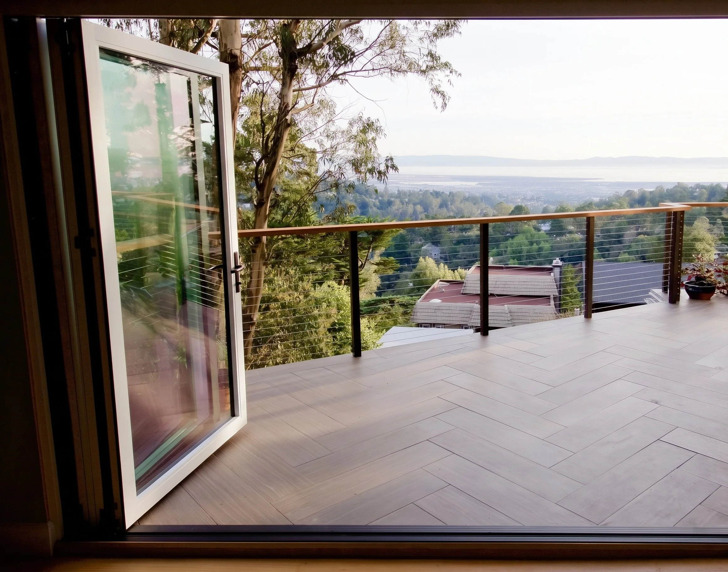 Deck seen through an open glass door, with a view toward the bay.