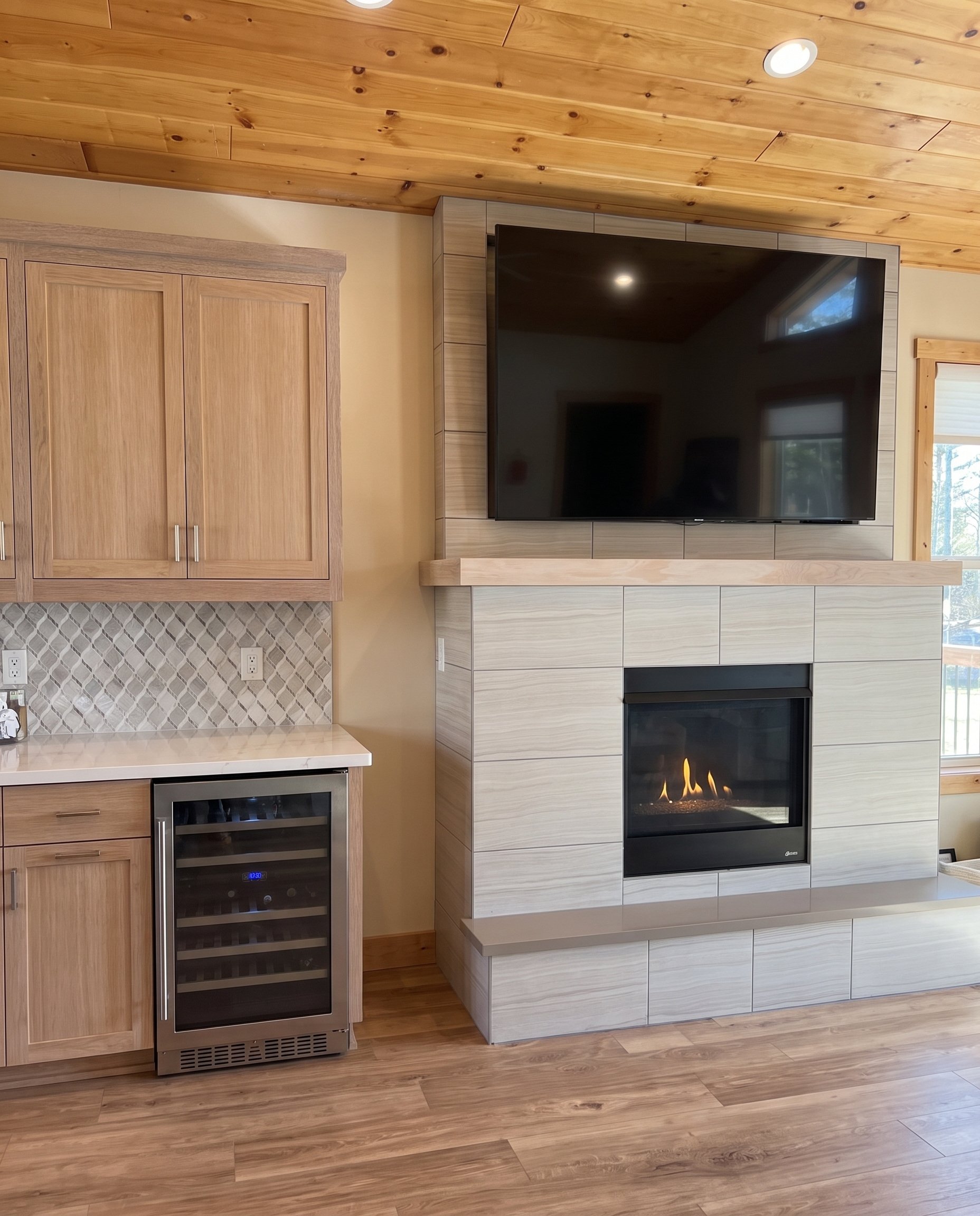 Tiled fireplace and TV under the wood plank ceiling.