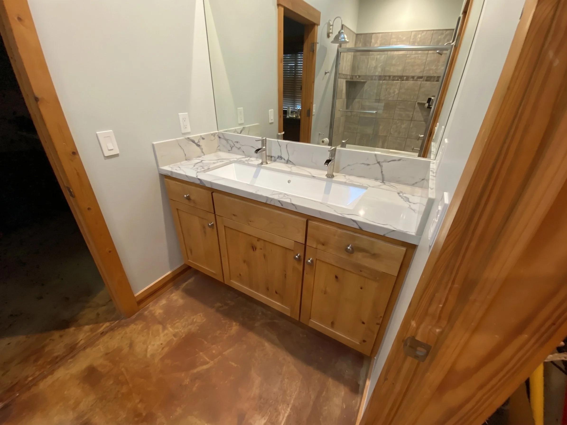 Bathroom in the same house: knotty alder vanity with a marble-look top and a two-faucet trough sink.