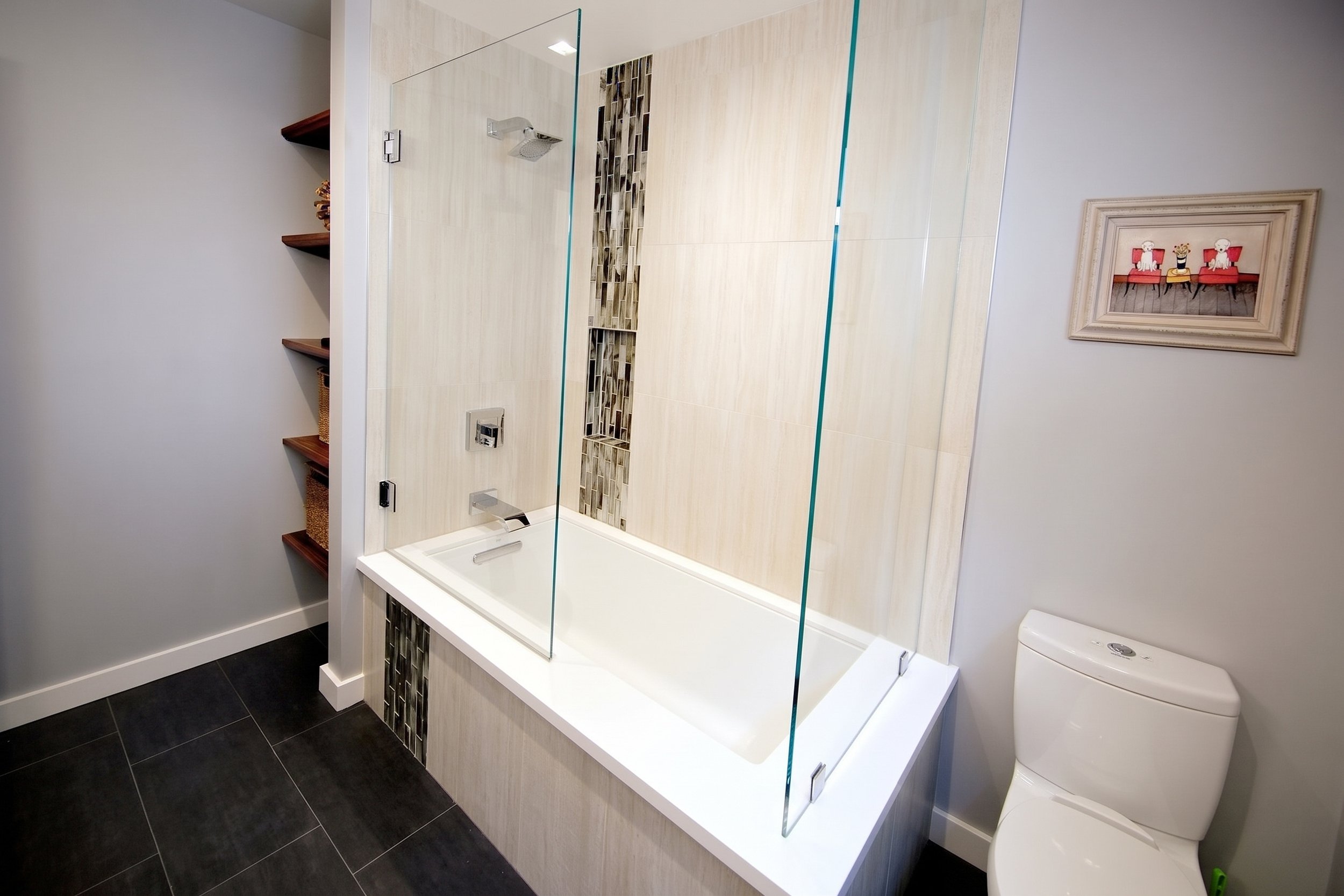 Tub and shower with a glass panel and a glass tile accent strip.
