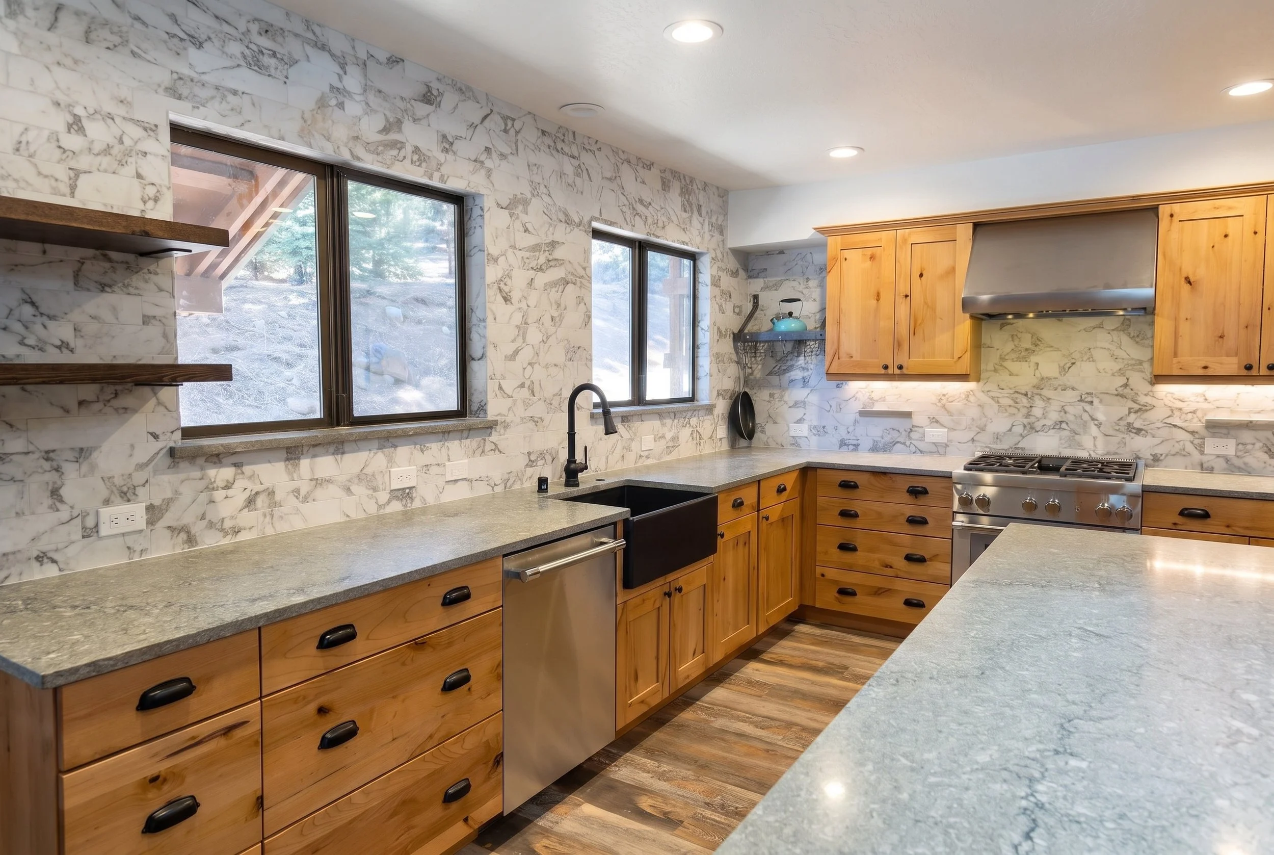 Sink run with a farmhouse sink under the windows and a stone backsplash.