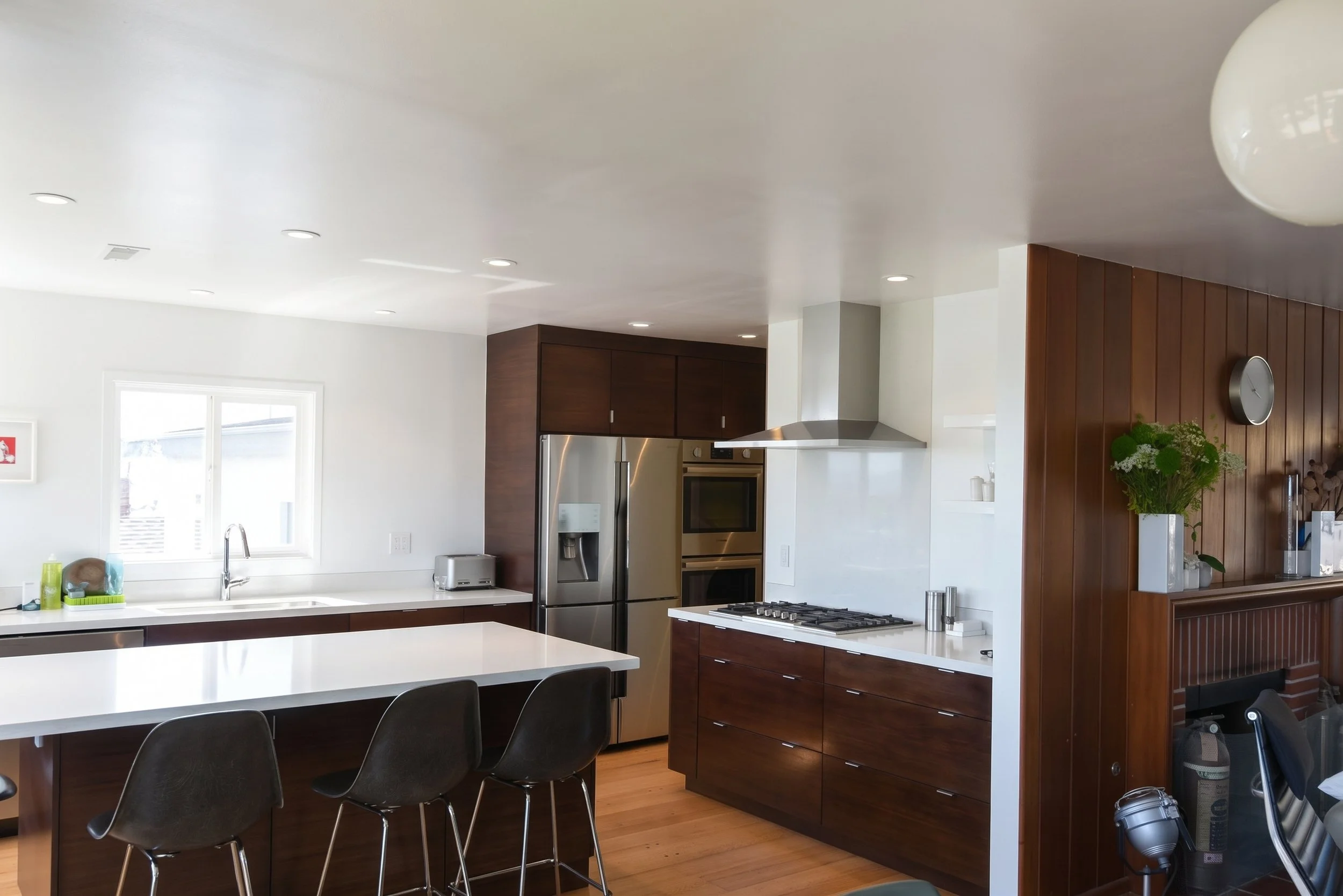 Island with seating facing the cooktop wall and hood.