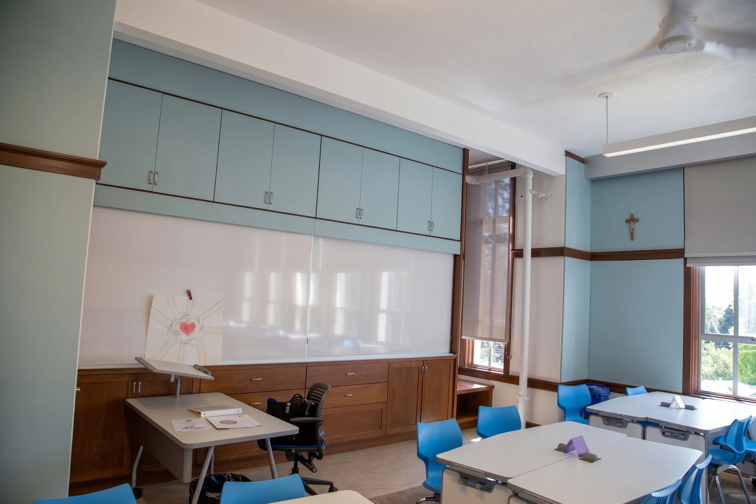 Upper storage cabinets and whiteboard wall in a classroom.