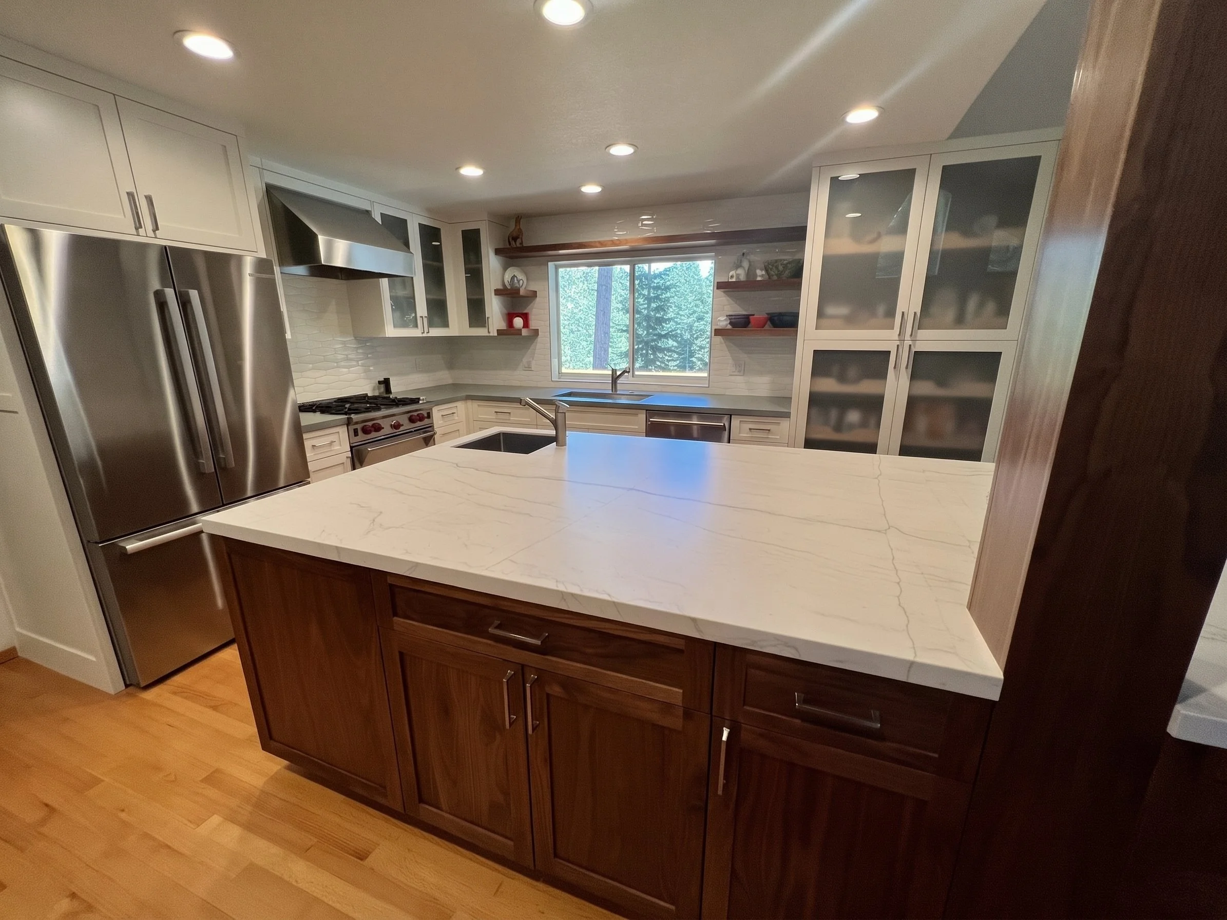 Island and stainless refrigerator, with the range and sink wall beyond.