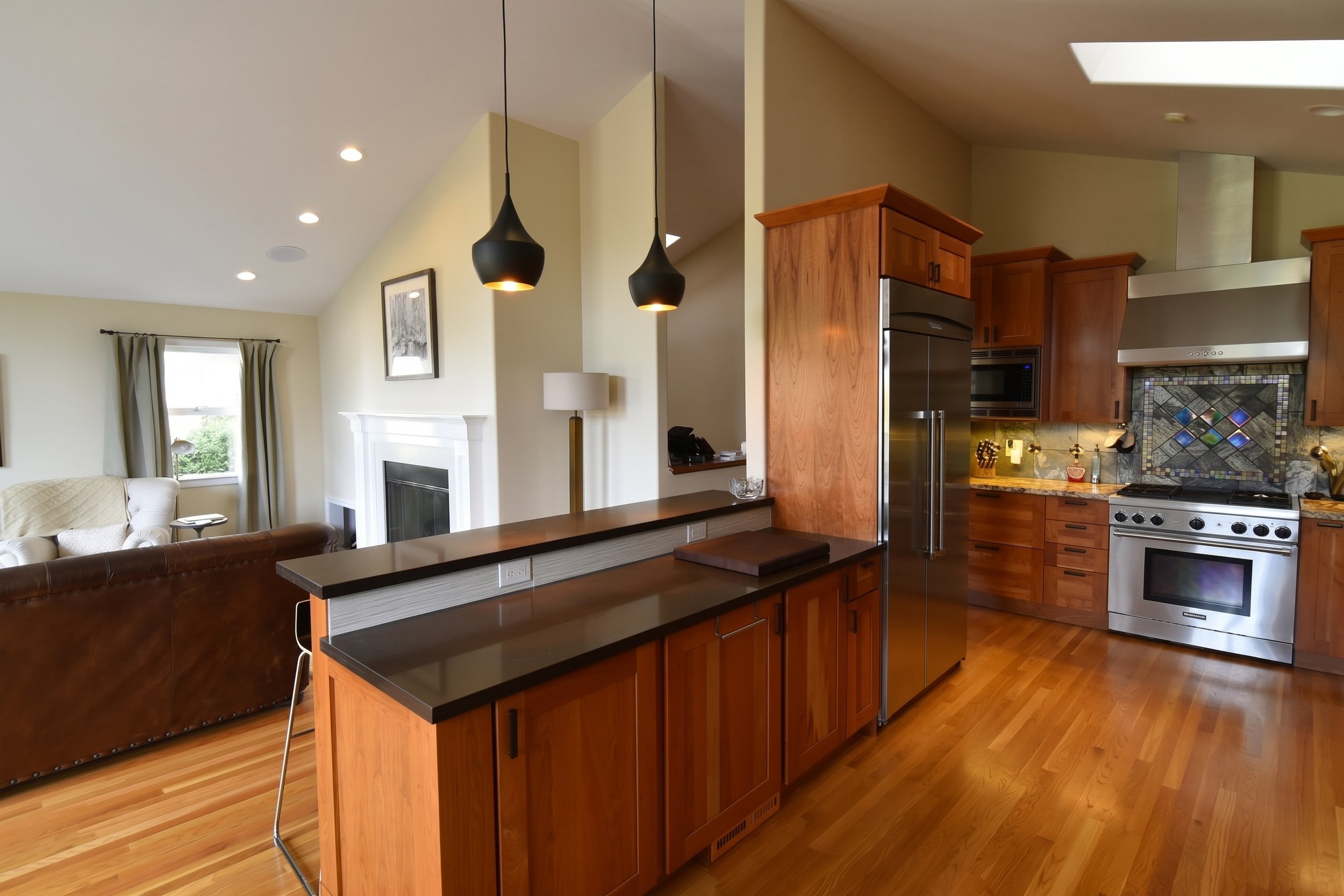 Kitchen with cherry cabinets, a raised breakfast bar and pendant lights.