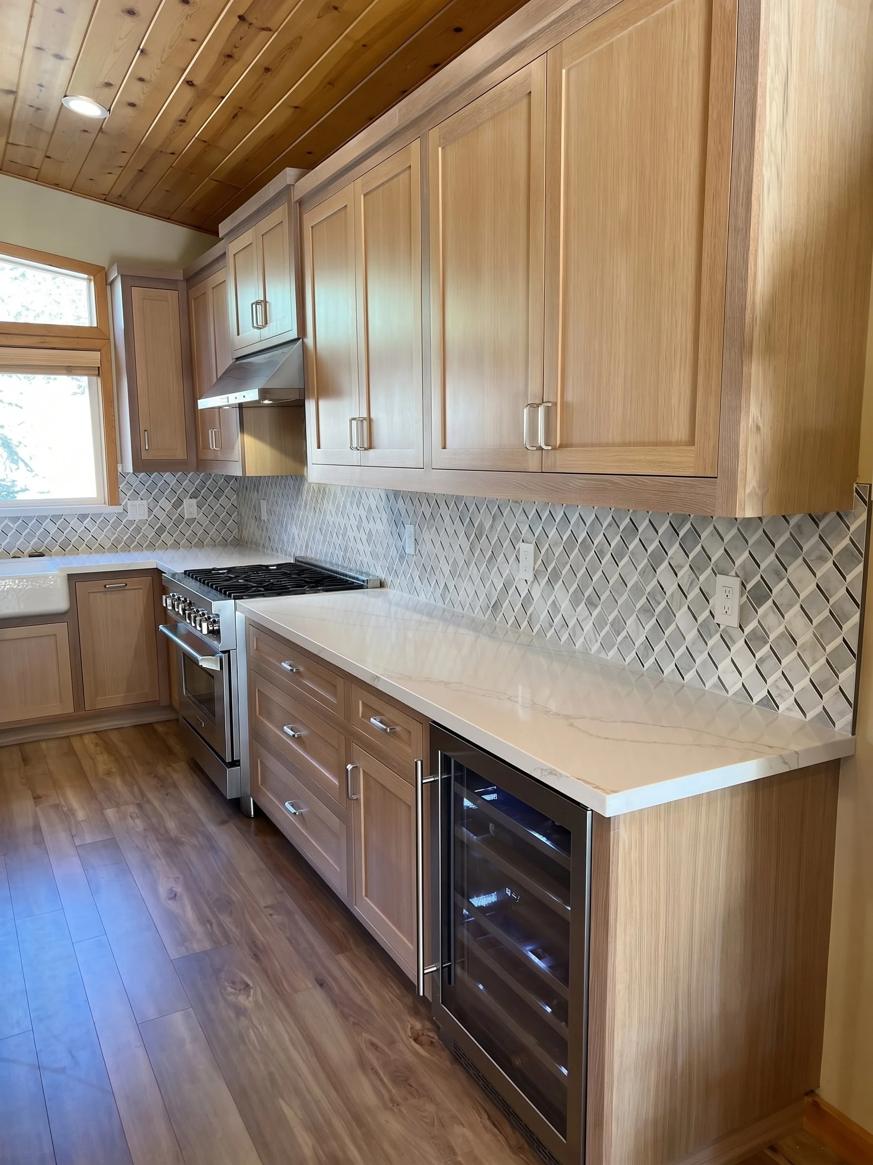 Cabinet run toward the range, ending in a built-in beverage refrigerator.