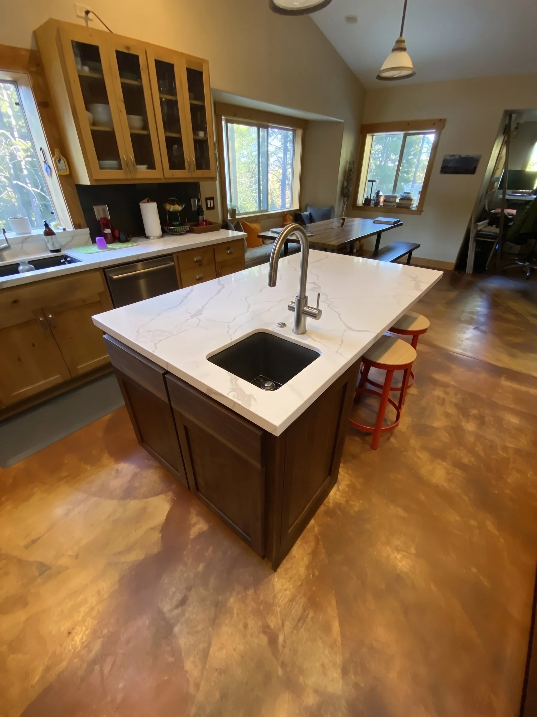 Dark wood island with a quartz top and an undermount sink, seen from above, with red stools.