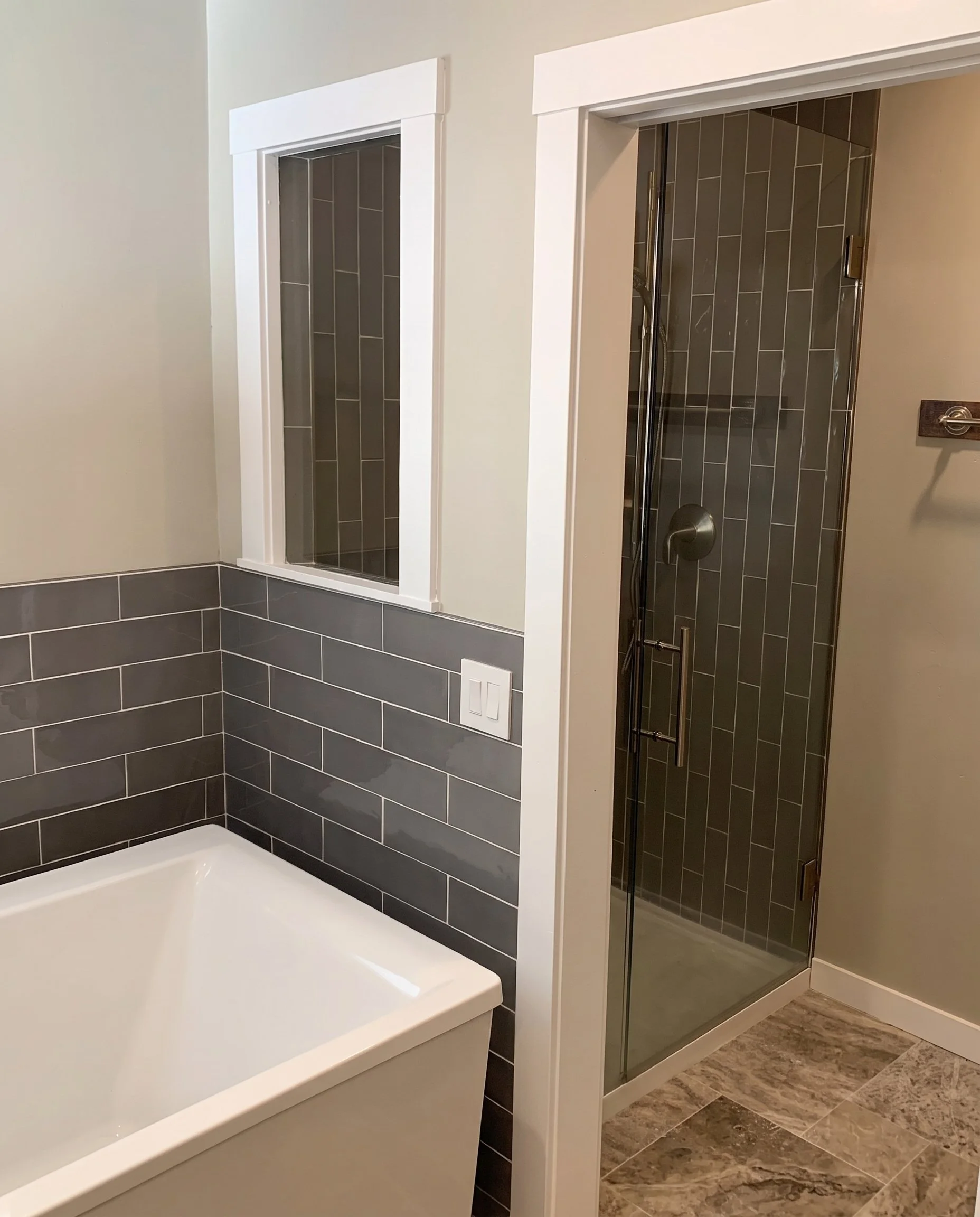 Soaking tub beside a tiled shower with a glass door.