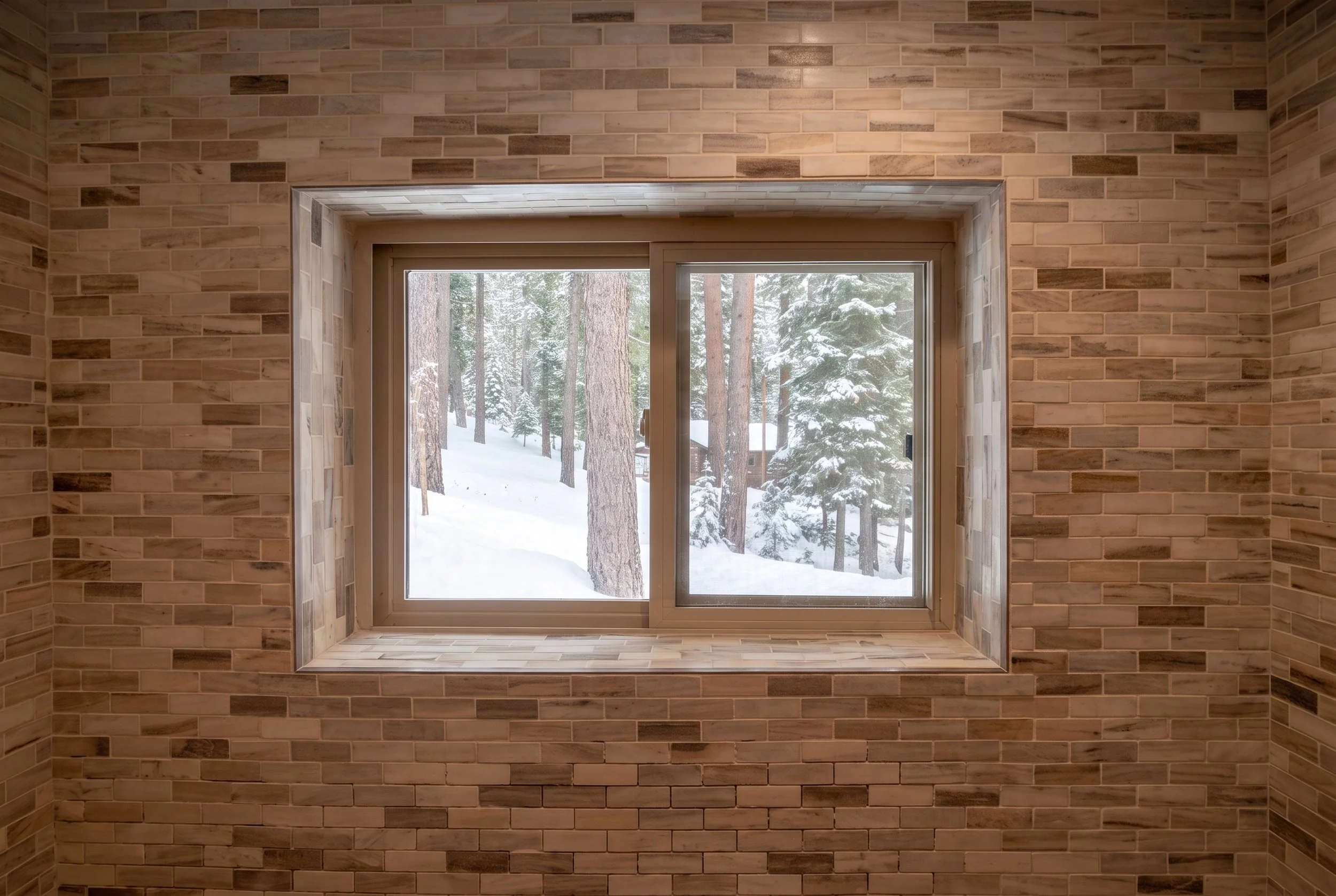 Window set into a fully tiled bathroom wall.