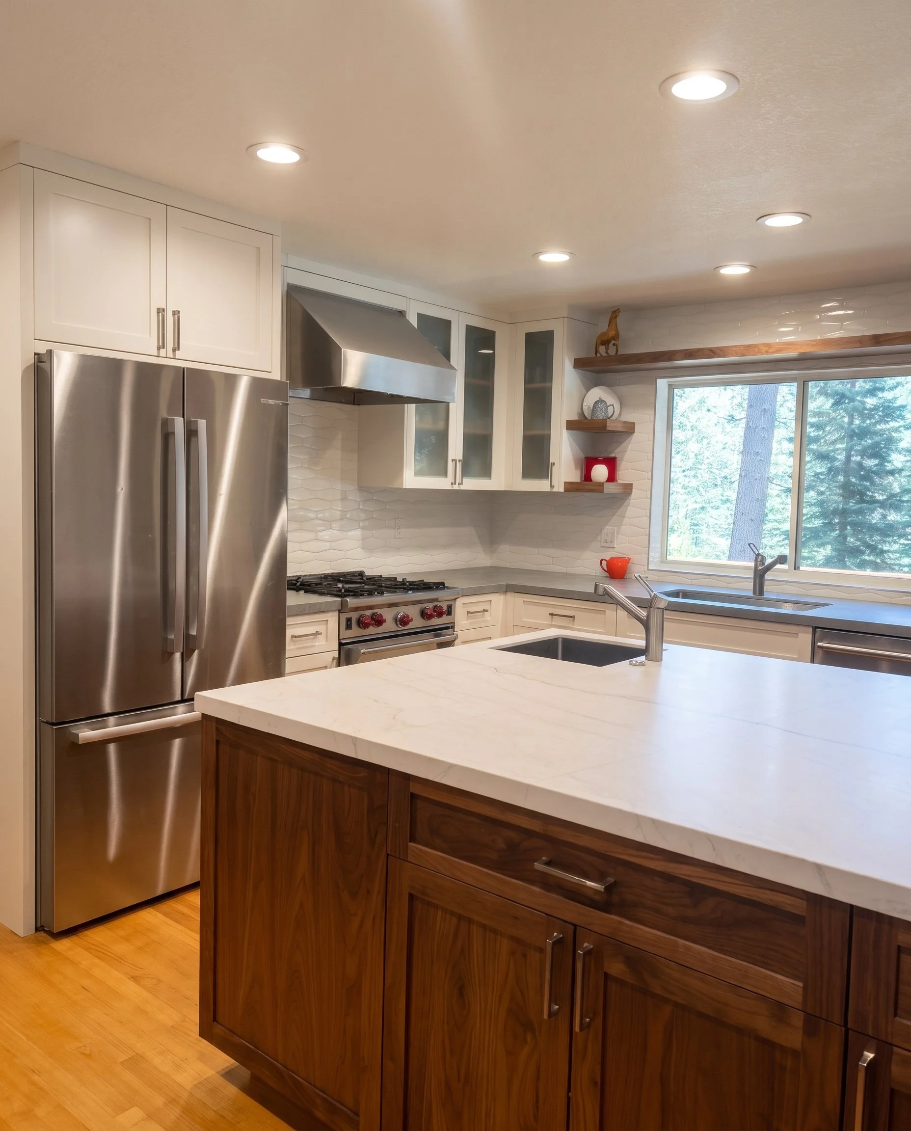 Dark wood island with a white stone top beside the stainless refrigerator.