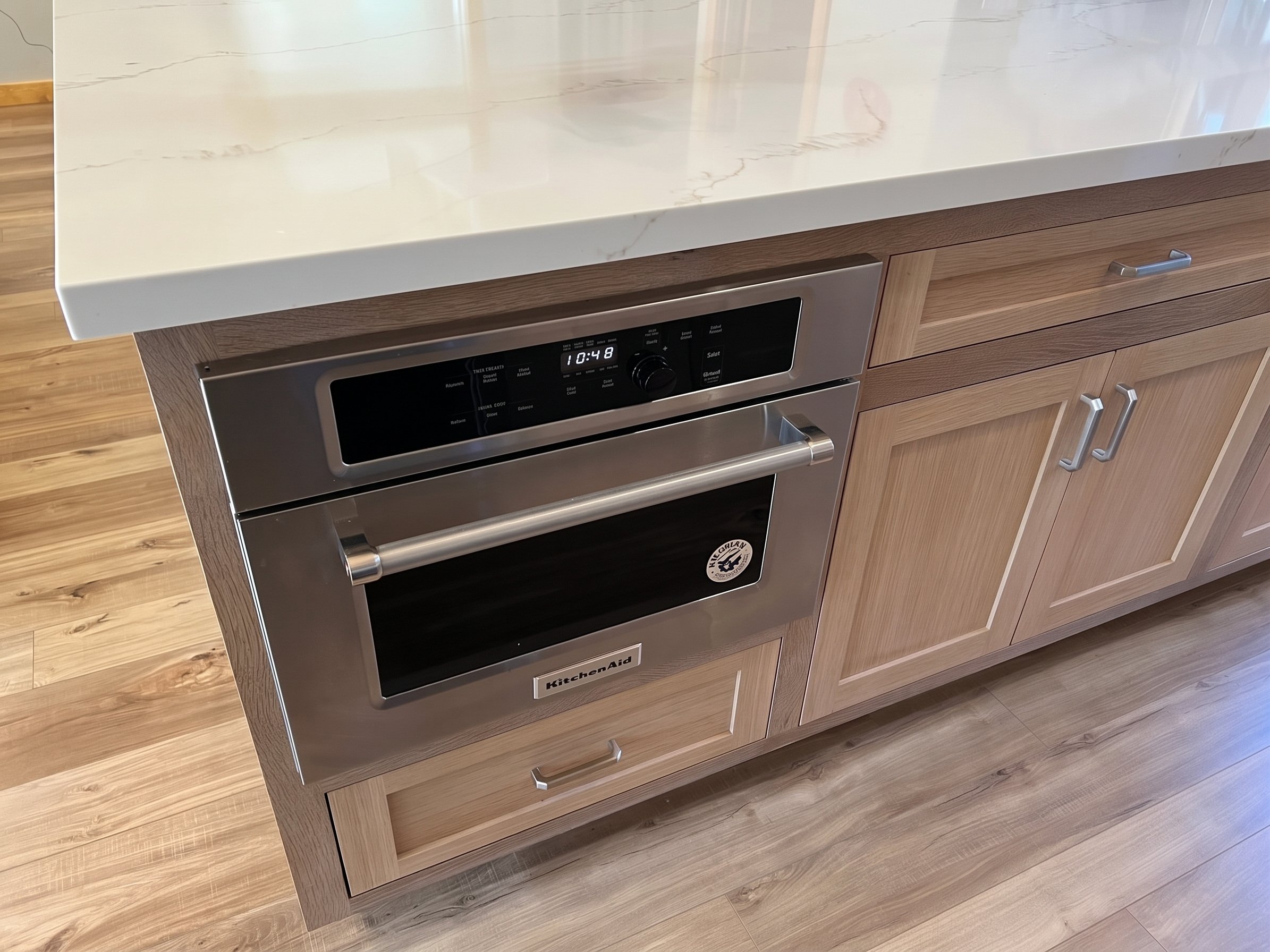 Microwave drawer built into the island under the white quartz top.