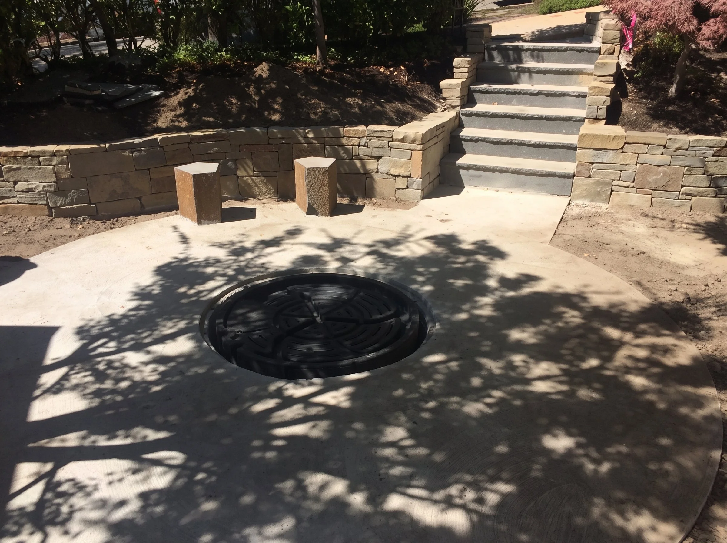 Paved circle with a fire pit and stone steps.