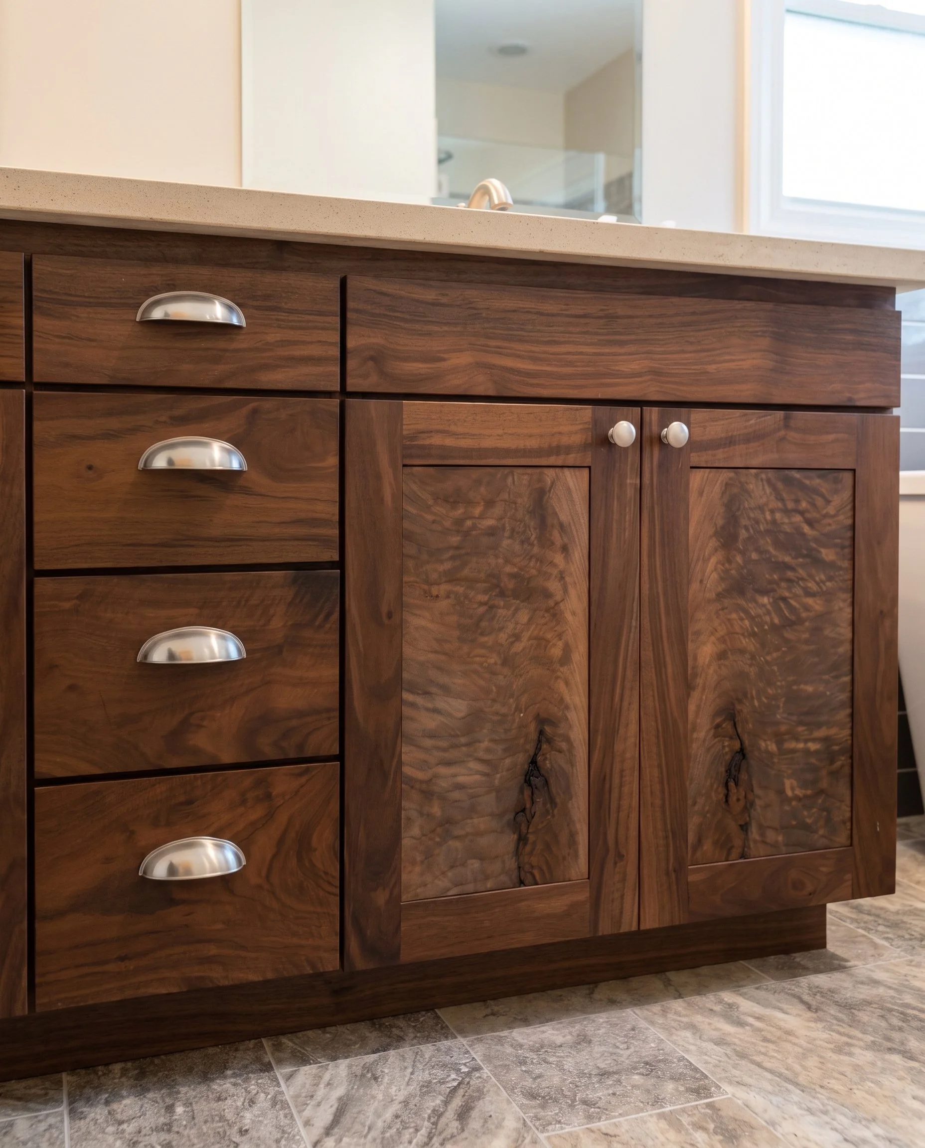 Dark wood bath vanity with cup pulls and a light stone top.