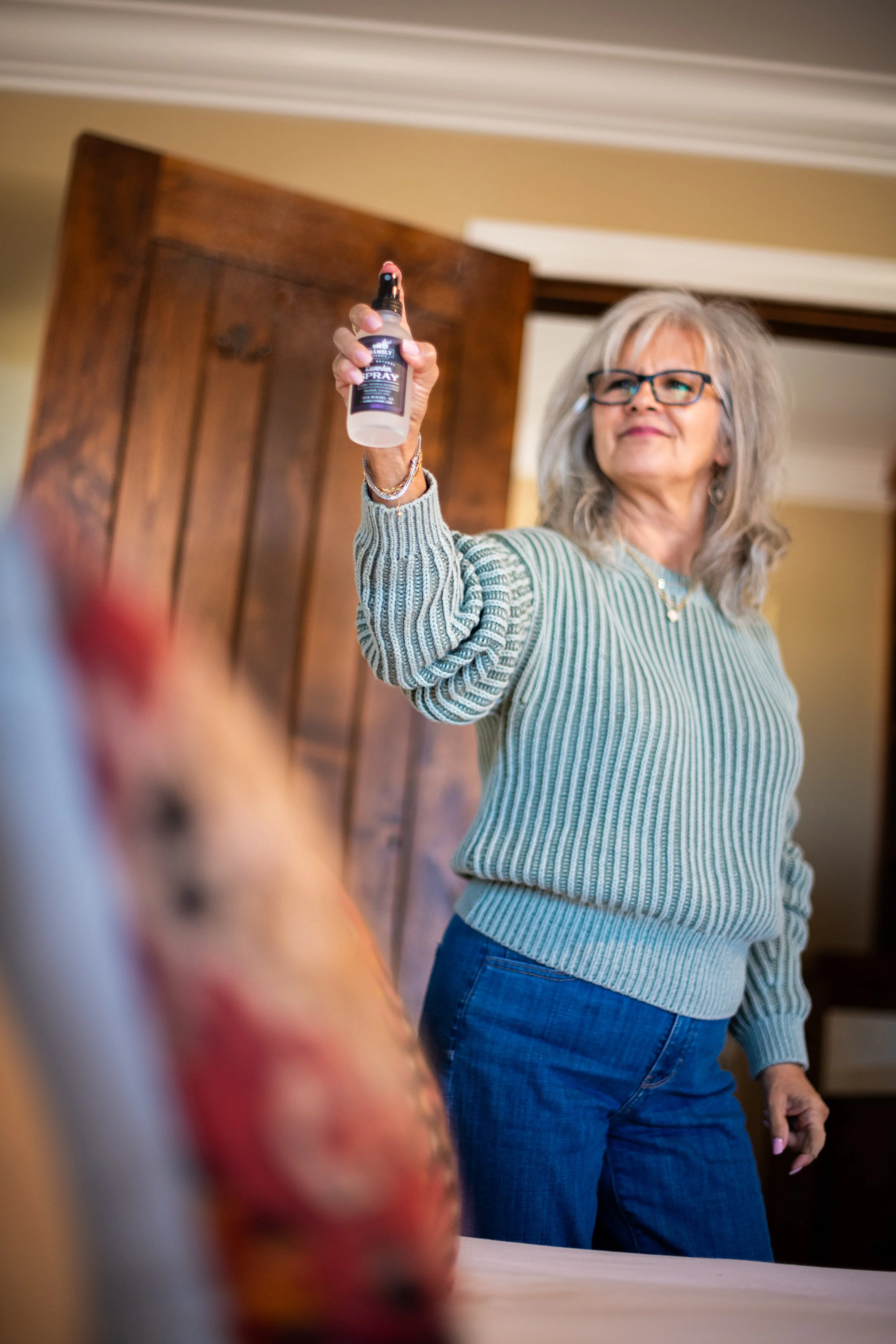 Woman using Lavender Linen and Room Spray over bed
