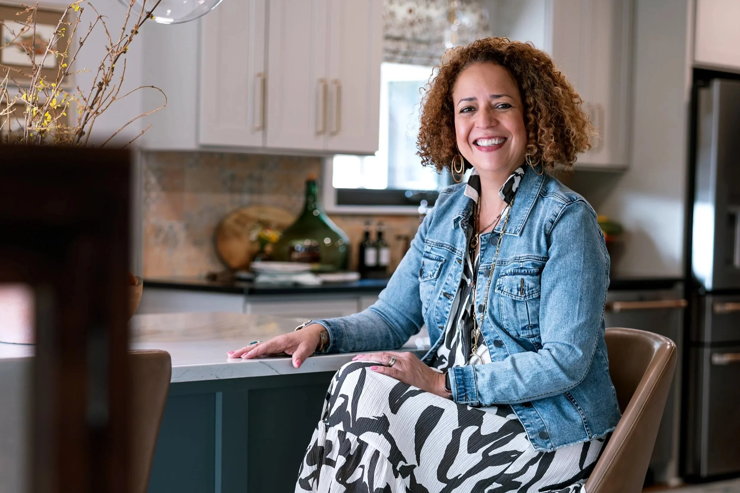 Gloria Staats, Owner of Peace of Mind Design sits at her kitchen smiling