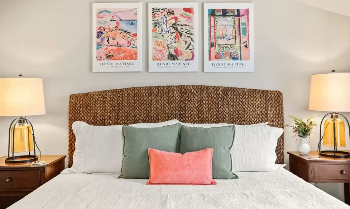 Professionally styled vacation rental bedroom featuring a coastal woven headboard, colorful Matisse art prints, and premium bedding, designed to increase nightly rates in Jacksonville, FL.